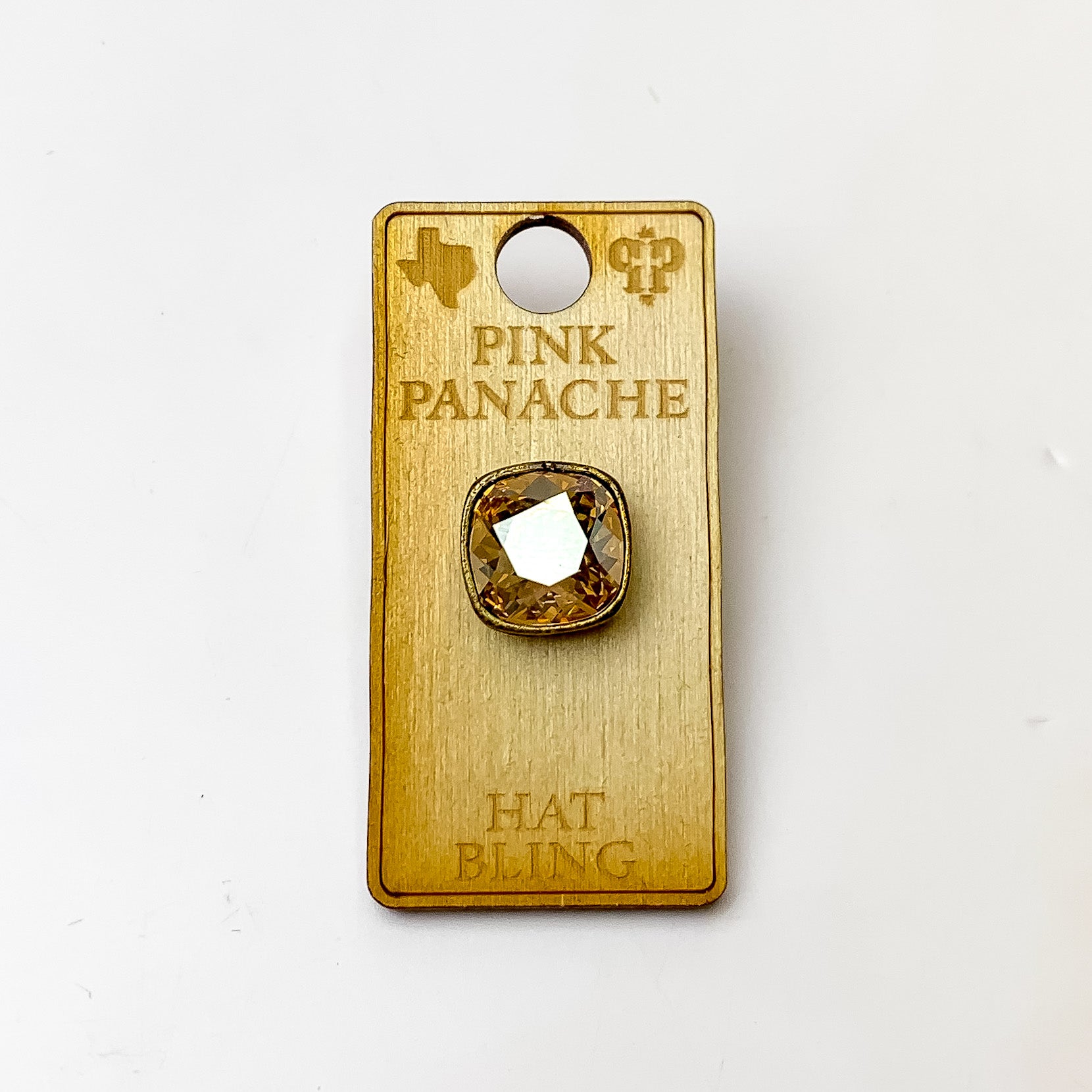 Bronze, square hat pin with a golden shadow cushion cut crystal. This hat pin is pictured on a wooden Pink Panache holder on a white background.