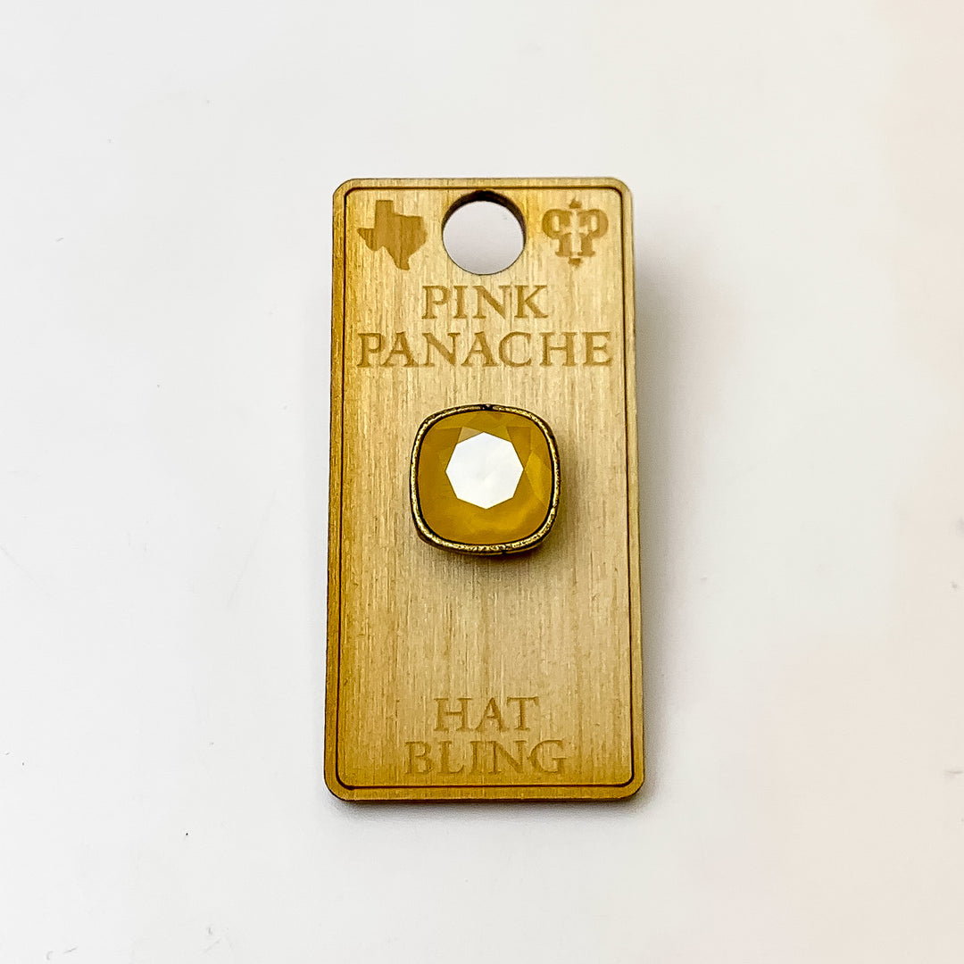 Bronze, square hat pin with a Buttercup Yellow cushion cut crystal. This hat pin is pictured on a wooden Pink Panache holder on a white background.