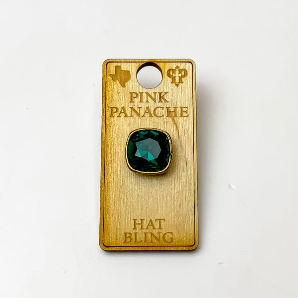 Bronze, square hat pin with a emerald cushion cut crystal. This hat pin is pictured on a wooden Pink Panache holder on a white background.