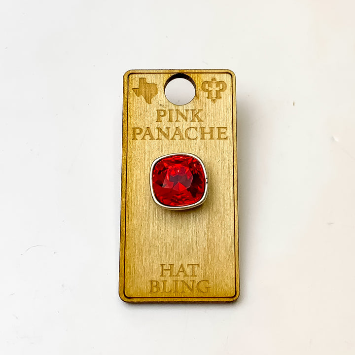 Silver, square hat pin with a light siam cushion cut crystal. This hat pin is pictured on a wooden Pink Panache holder on a white background.