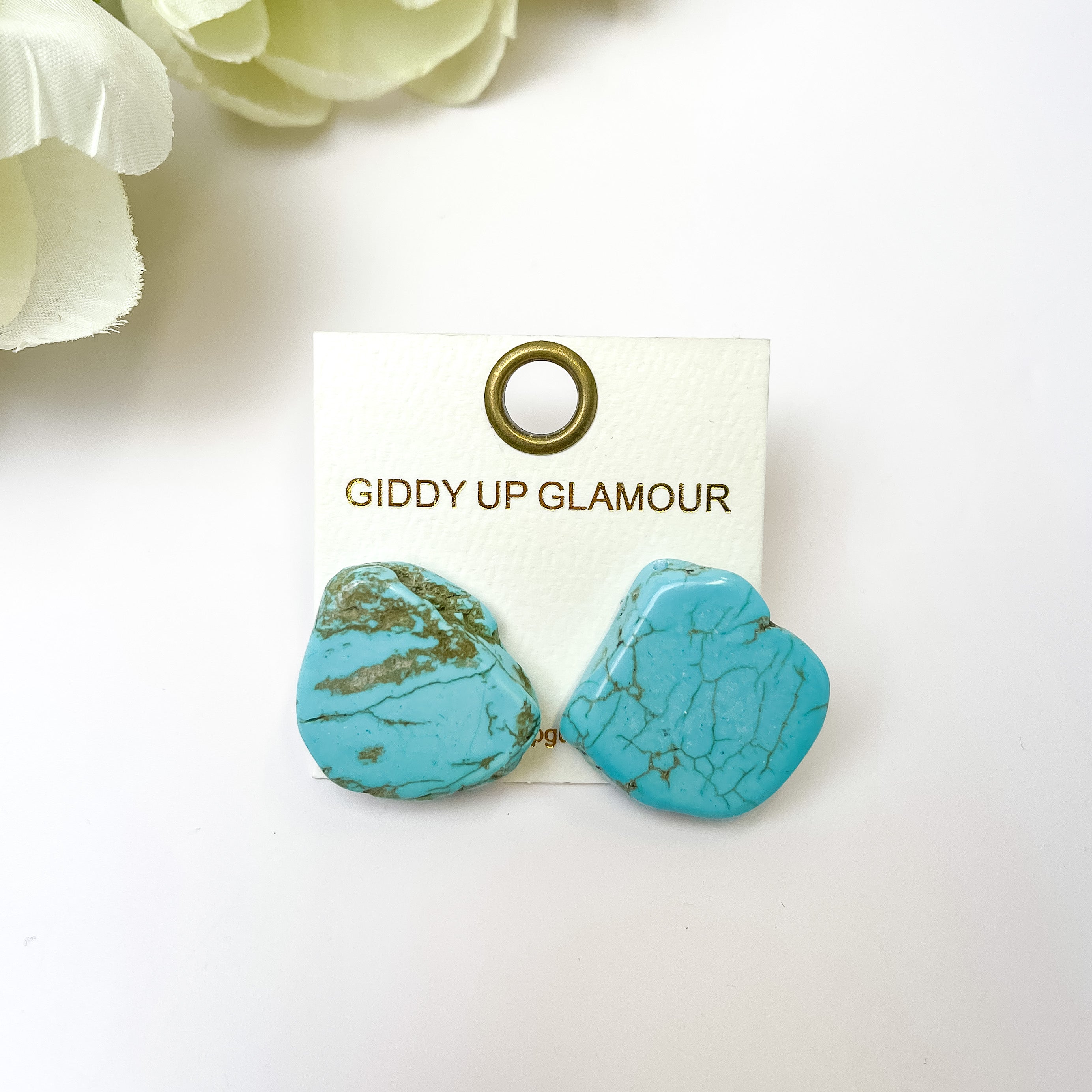 Turquoise Slab Stud Earrings. Pictured on a white background with flowers in the top left corner.