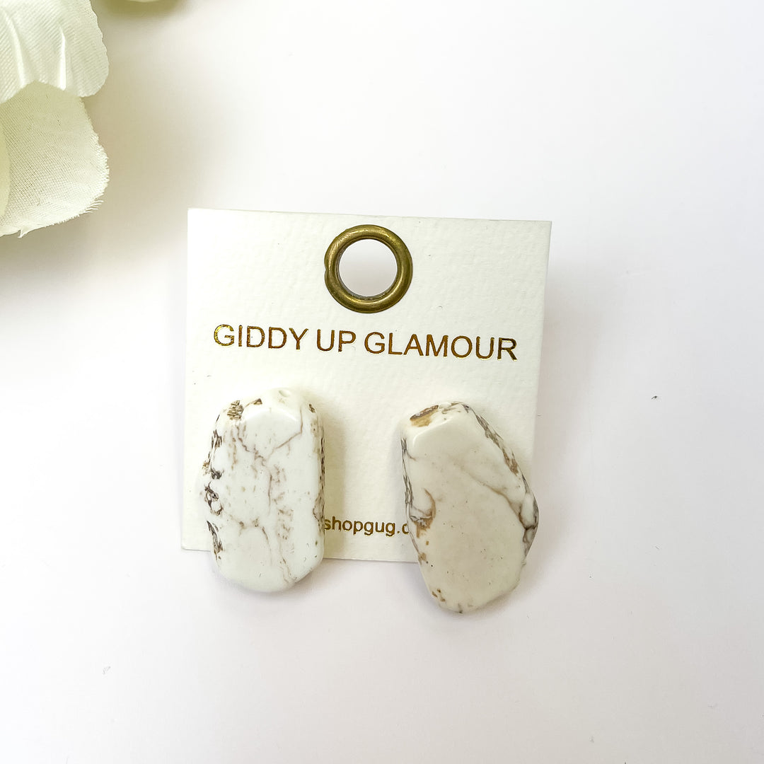 White marbled Slab Stud Earrings. Pictured on a white background with a white flower in the top left corner.