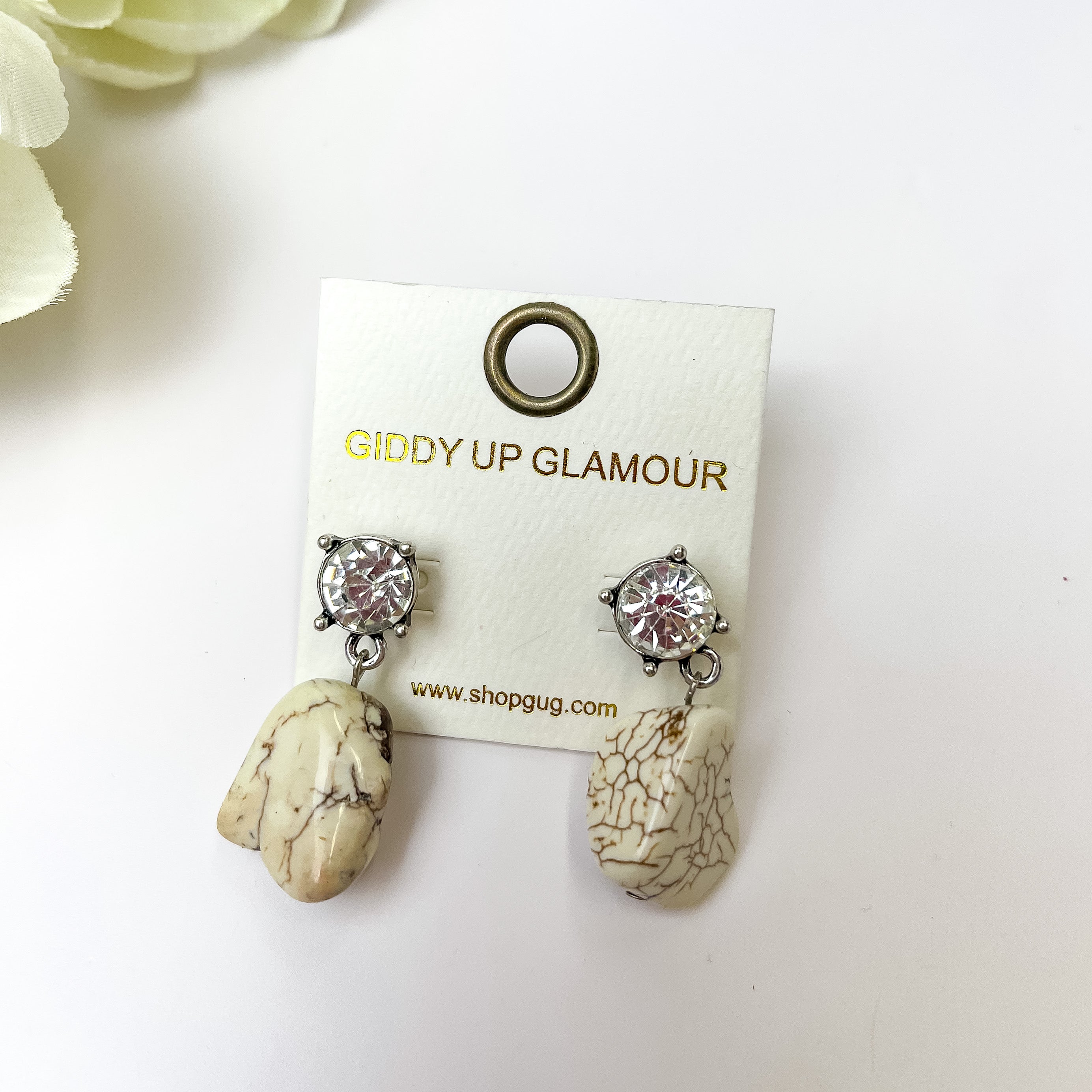 White Marbled Drop Earrings With Clear Crystal Studs. Pictured on a white bckground with a white flower in the top left corner. 