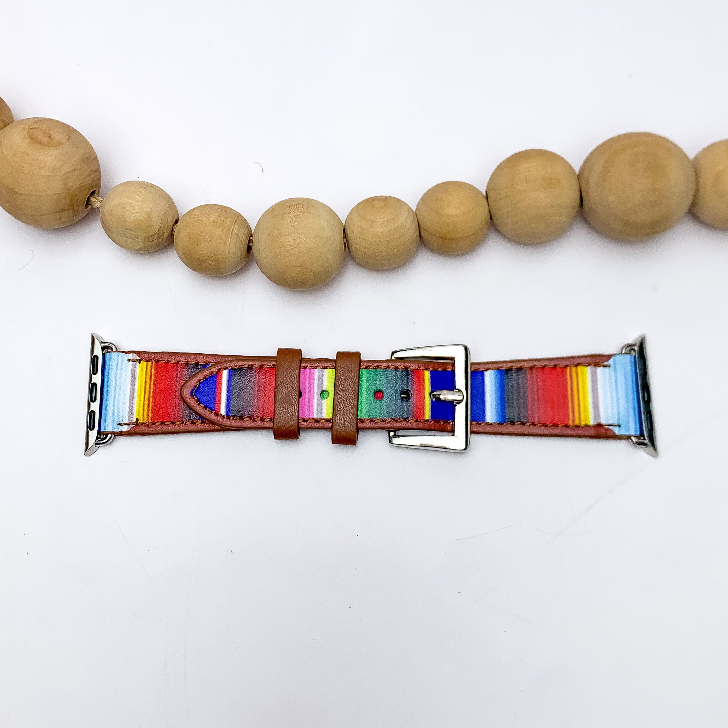 Stripped Apple Watch Band in Multicolor. Pictured on a white background with wood beads above the band for decoration. 