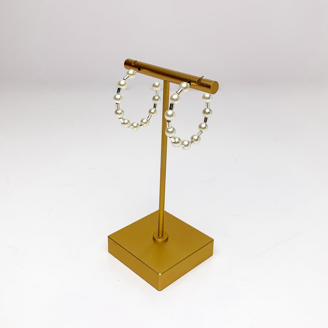 Pretty Pearl Small Hoop Earrings in Silver Tone. Pictured on a gold platform with a white background.