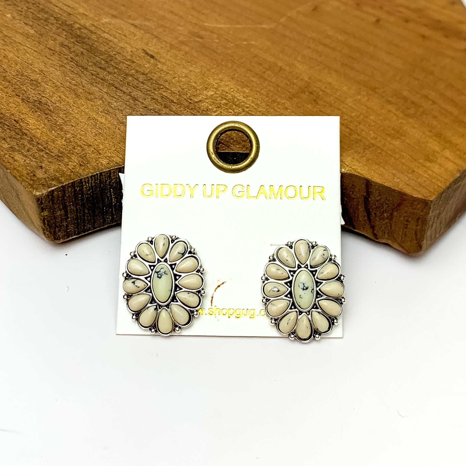 Silver Tone Concho Cluster Oval Earrings in Ivory. Pictured on a white background with the earrings laying against a wood piece.