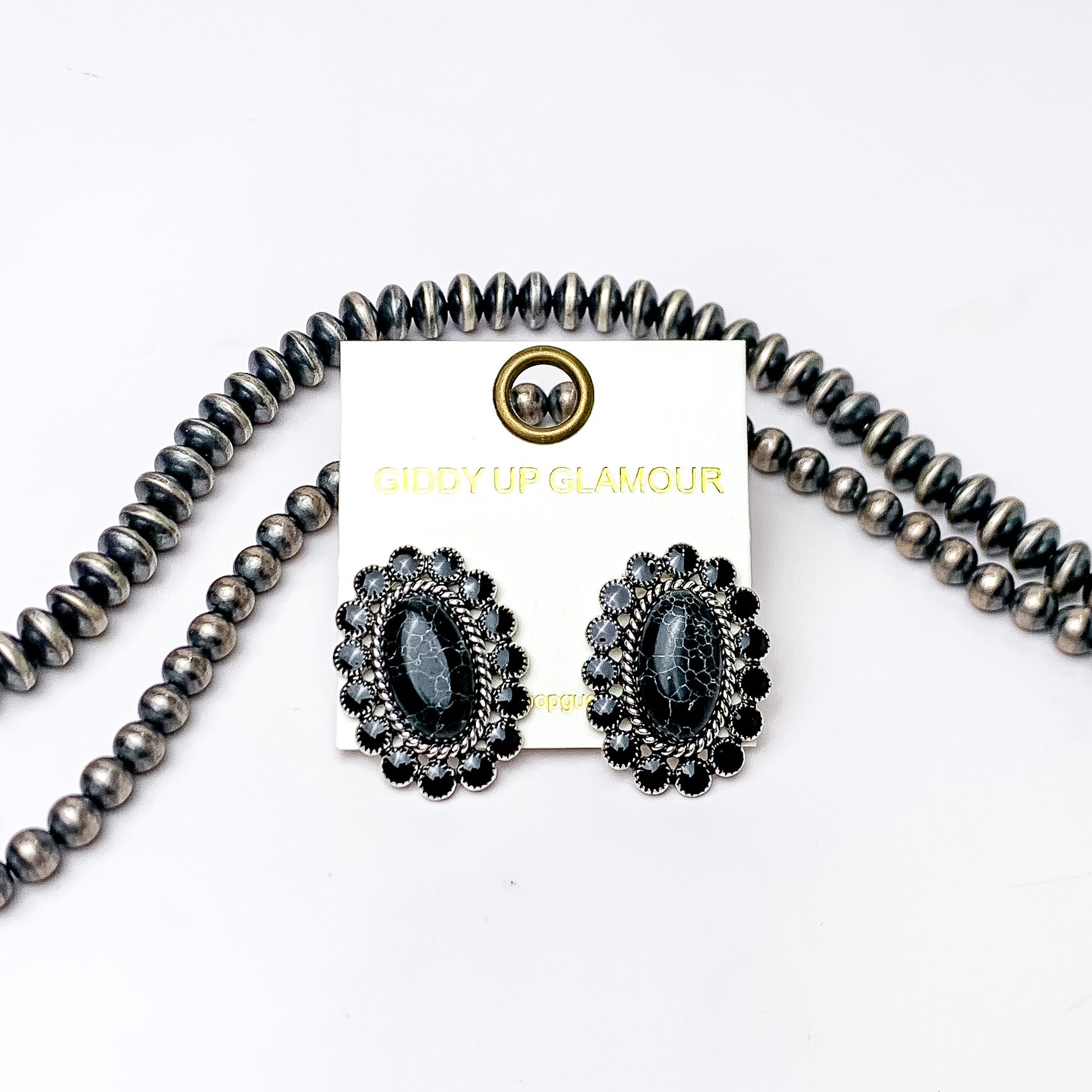 Faux Black Stone Concho Post Earrings. Pictured on a white background with beads behind the earrings for decoration.