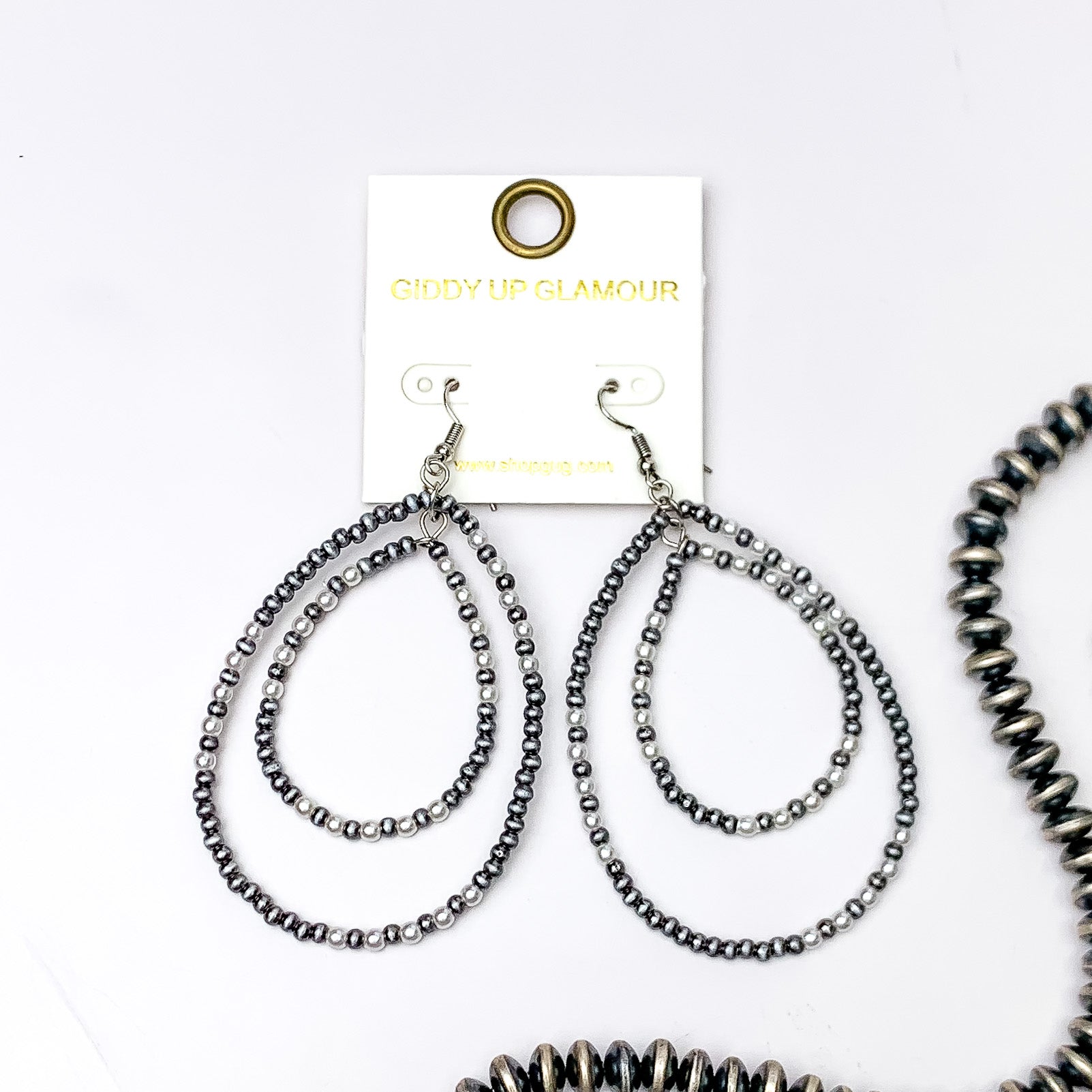 Double teardrop beaded earrings with silver and white beads, These earrings are pictured on a white background with silver beads on the right side bottom of the picture. 