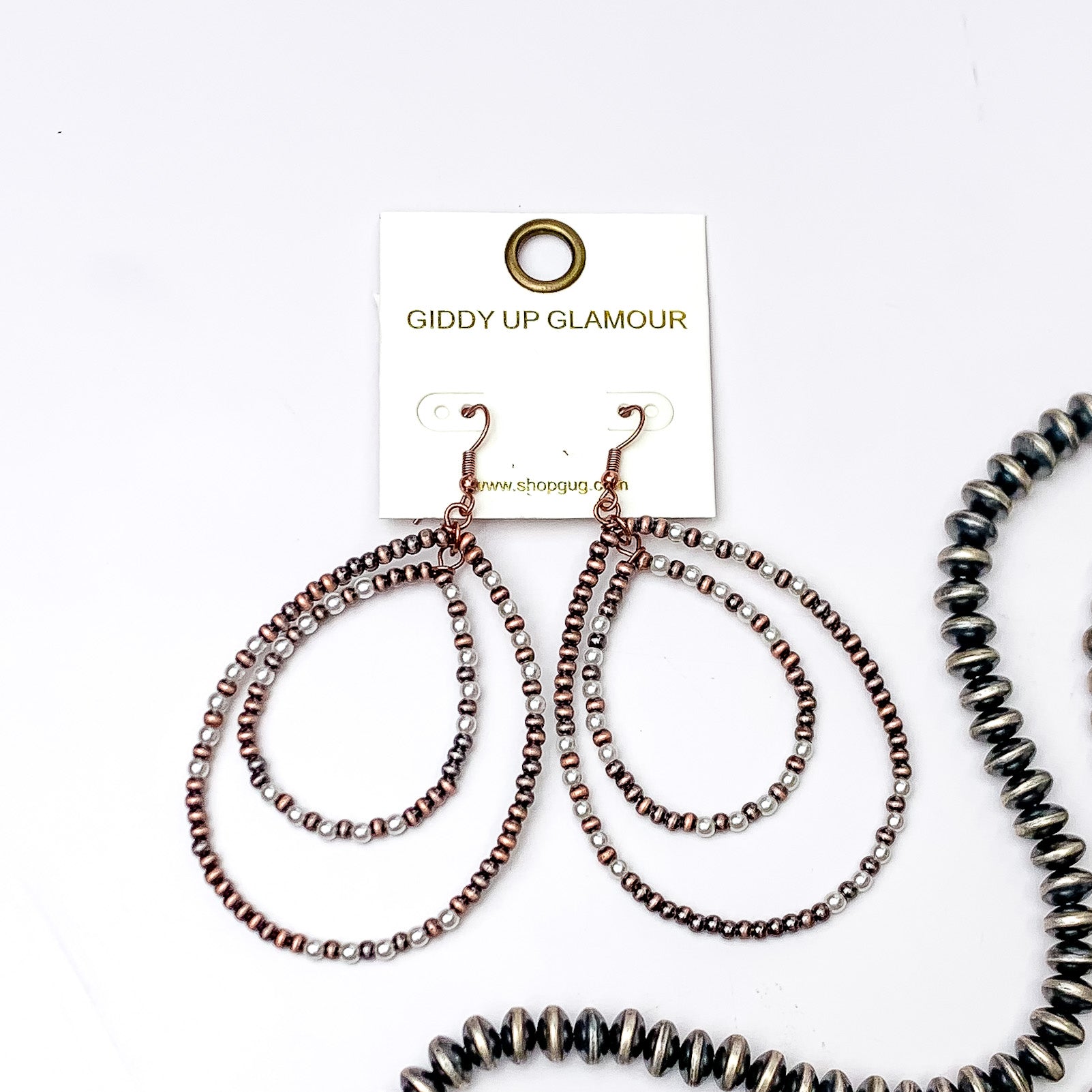 Double teardrop beaded earrings with copper and white beads, These earrings are pictured on a white background with silver beads on the right side bottom of the picture. 