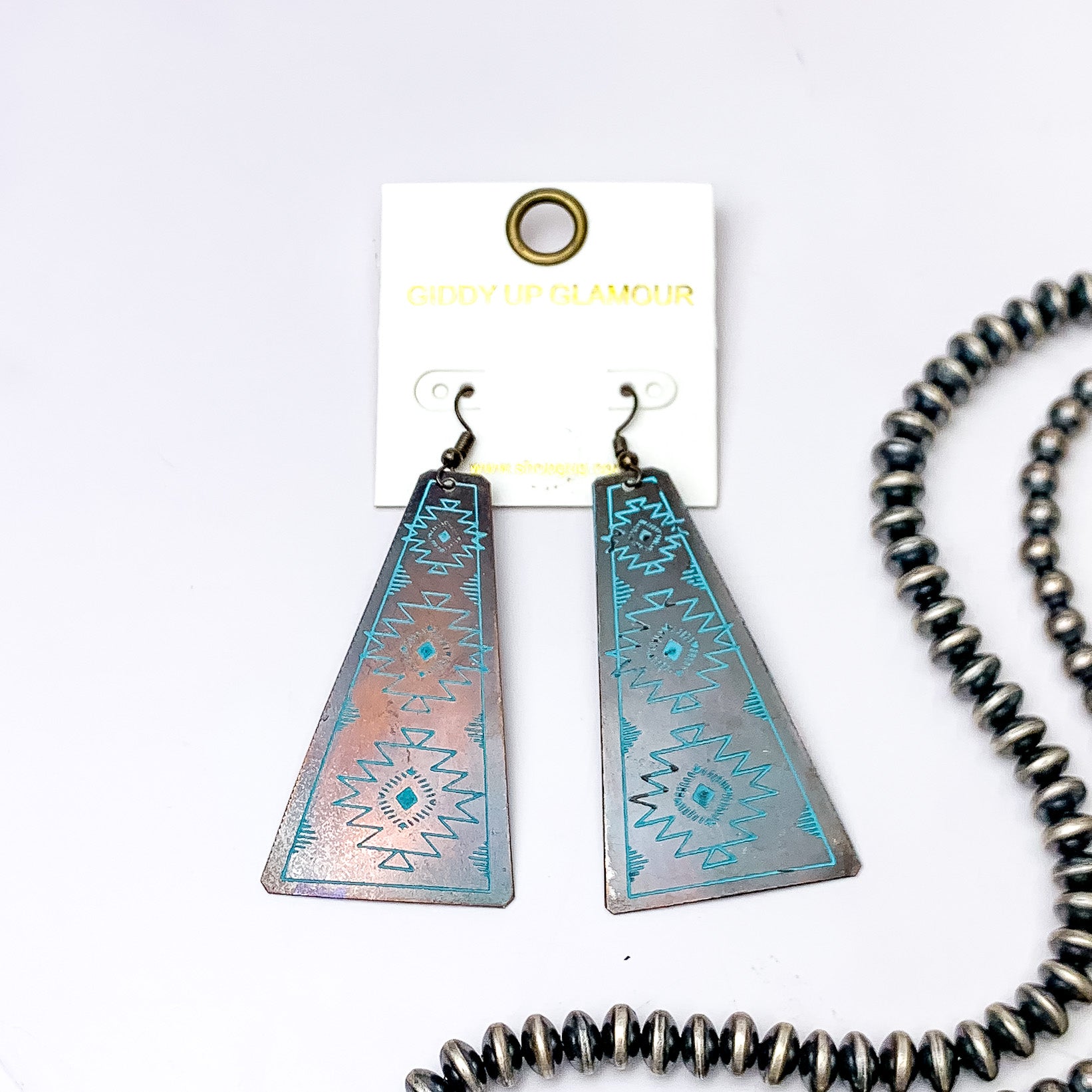 Aztec Tooled Earrings in Turquoise and Copper Tone. Pictured on a white background with beads to the right of the earrings for decoration.