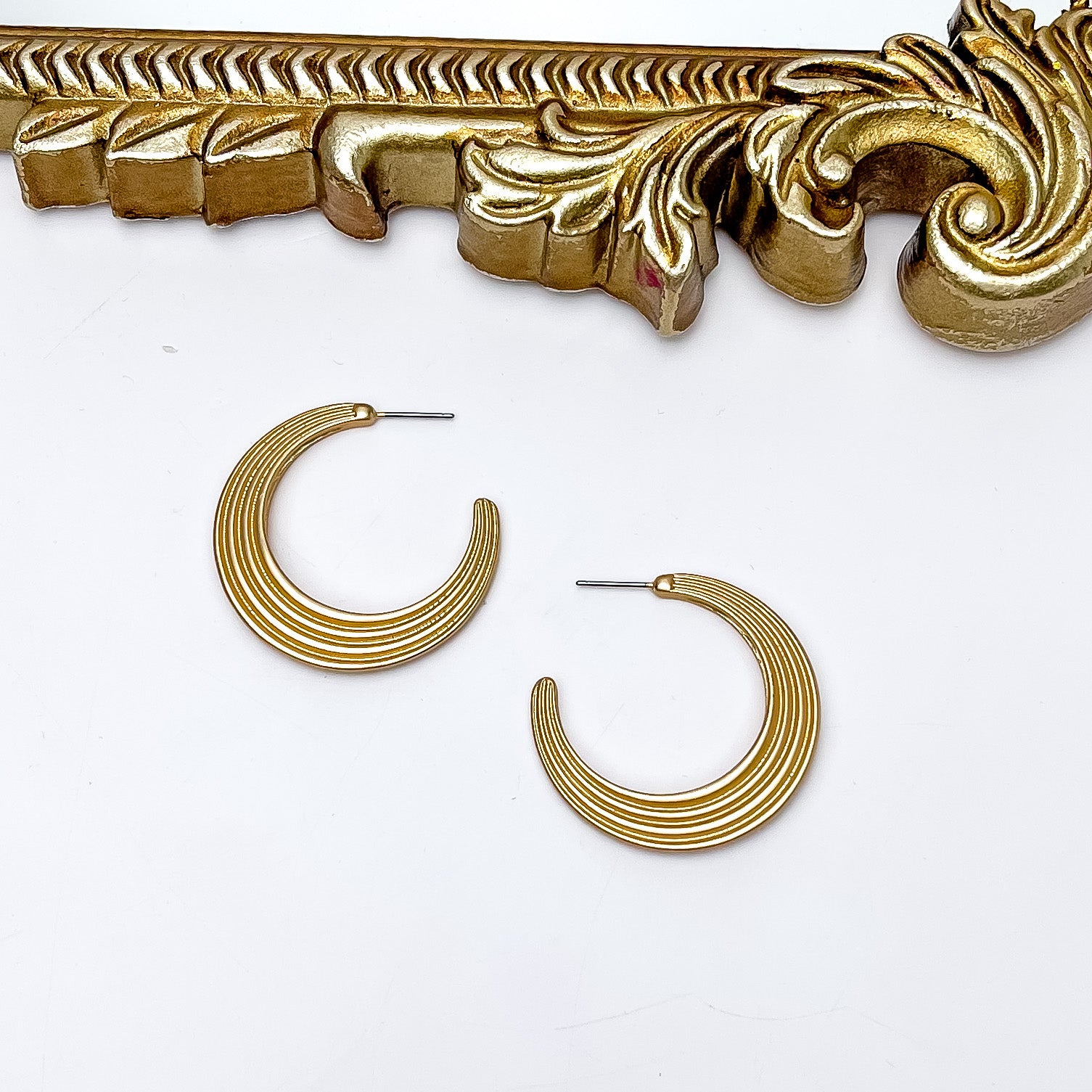 Livin' Life Gold Tone Large Hoop Earrings. Pictured on a white background with a gold frame above the earrings.