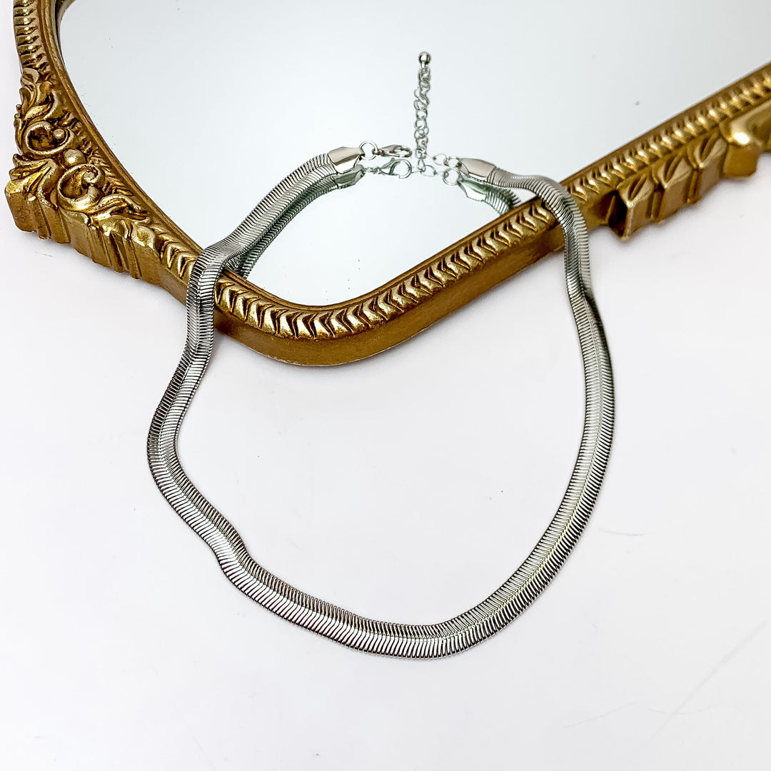 Daily Basis Silver Tone Chain Necklace. Pictured on a white background with part of the necklace on a mirror with a gold frame.