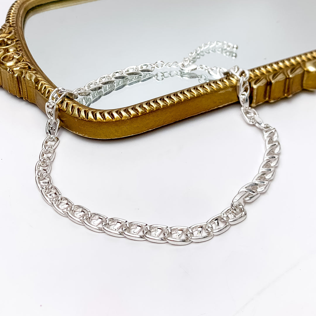Plain As Day Silver Tone Chain Necklace. Pictured on a white background with part of the necklace laying on a gold trimmed mirror.