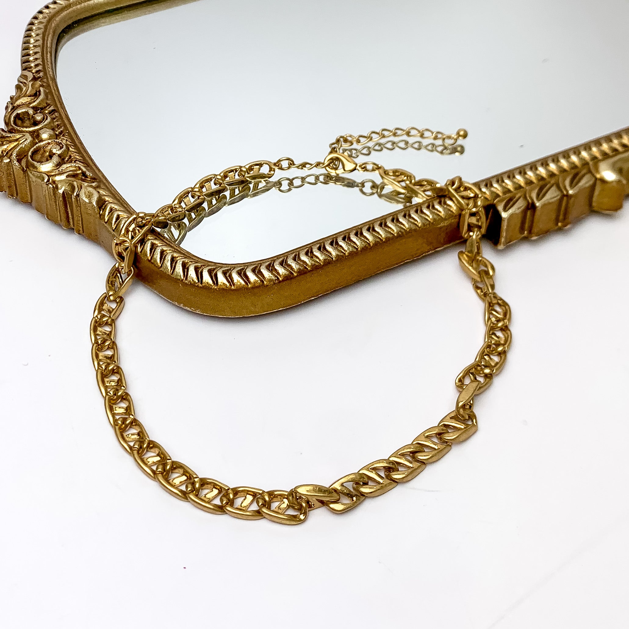 Plain As Day Gold Tone Chain Necklace. Pictured on a white background with part of the necklace laying on a gold trimmed mirror.