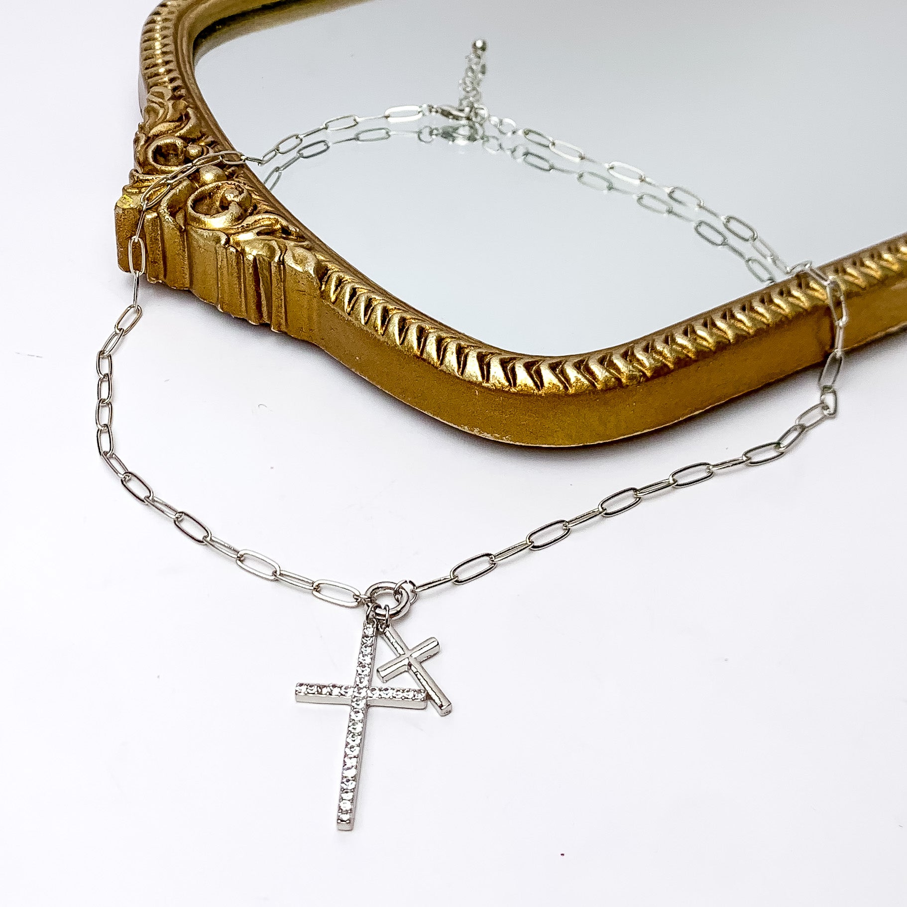 Silver Tone Double Cross Chain Necklace With Clear Crystals. Pictured on a white background with part of the necklace on a gold trimmed necklace.