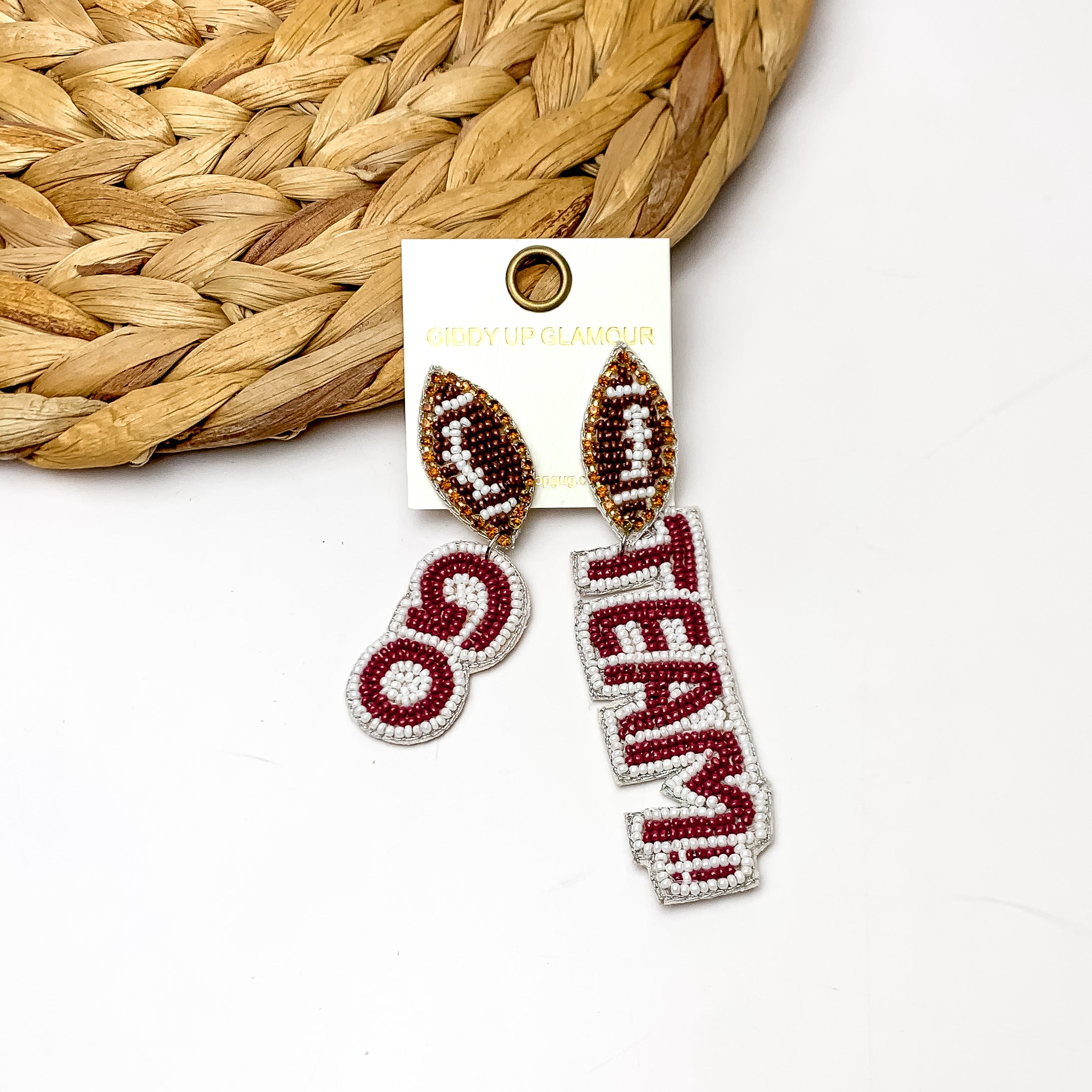 " Go Team!!" Beaded Earrings With Football Posts in Maroon and White. These earrings are laying against a woven piece with a white background behind it.