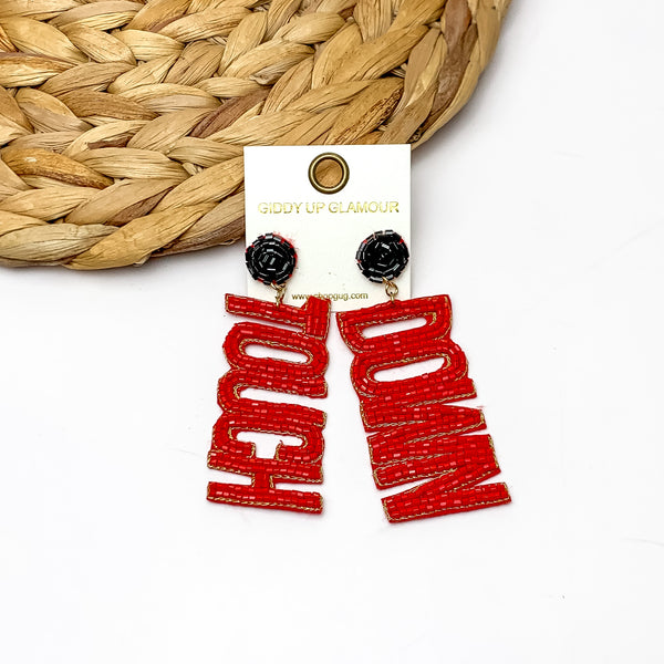 Beaded Touch Down Post Back Earrings in Red and Black. The earrings are laying against a woven piece. The background of the picture is white.
