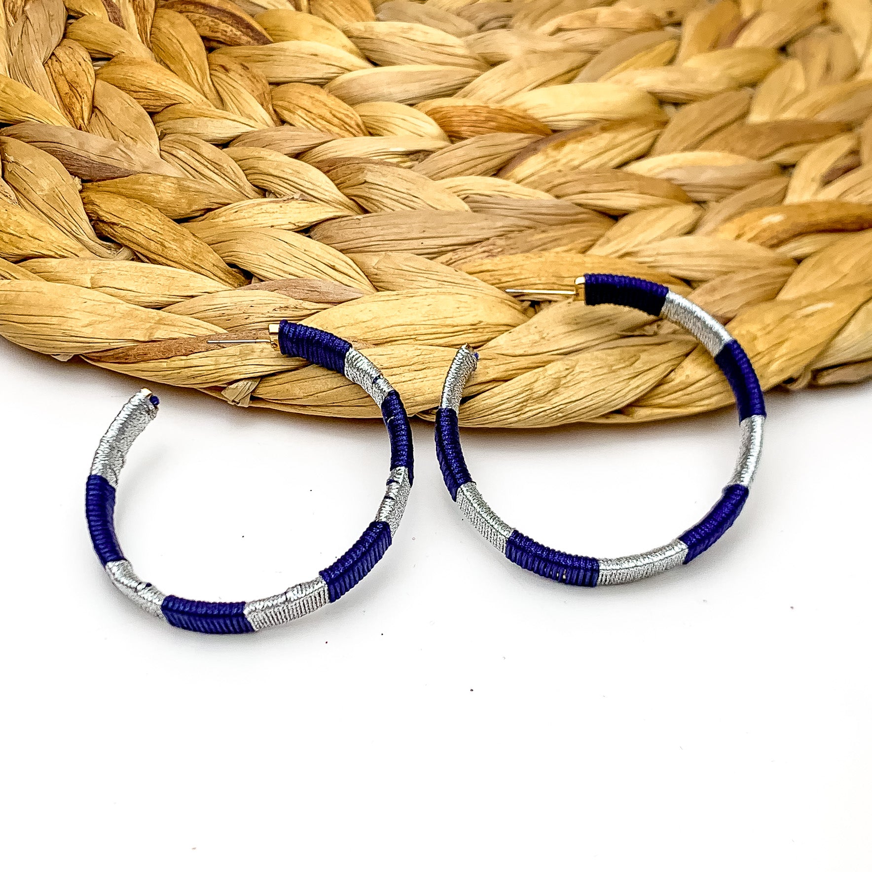 Game Day Glam Colored Hoop Earrings in Navy and Silver. The two colored hoops are laying against a woven decoration with a white background.