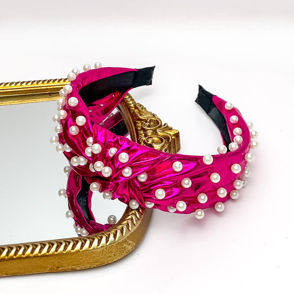 Pearl Detailed Knot Headband in Hot Pink. Pictured on a white background with the headband on a gold trimmed mirror.