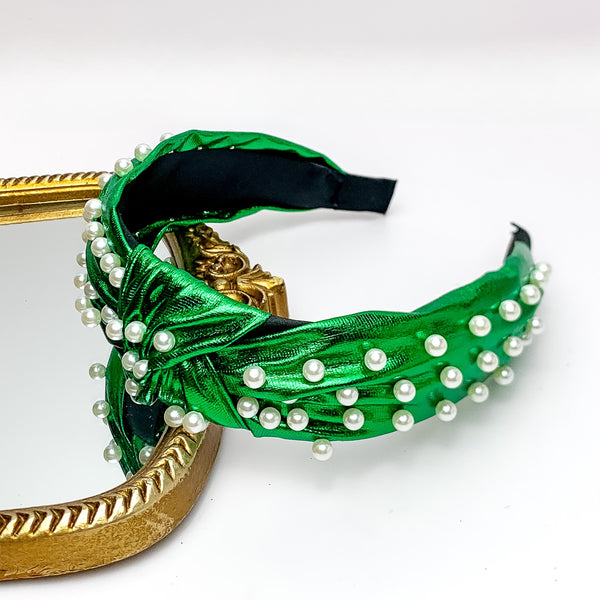 Pearl Detailed Knot Headband in Green. Pictured on a white background with the headband on a gold trimmed mirror.