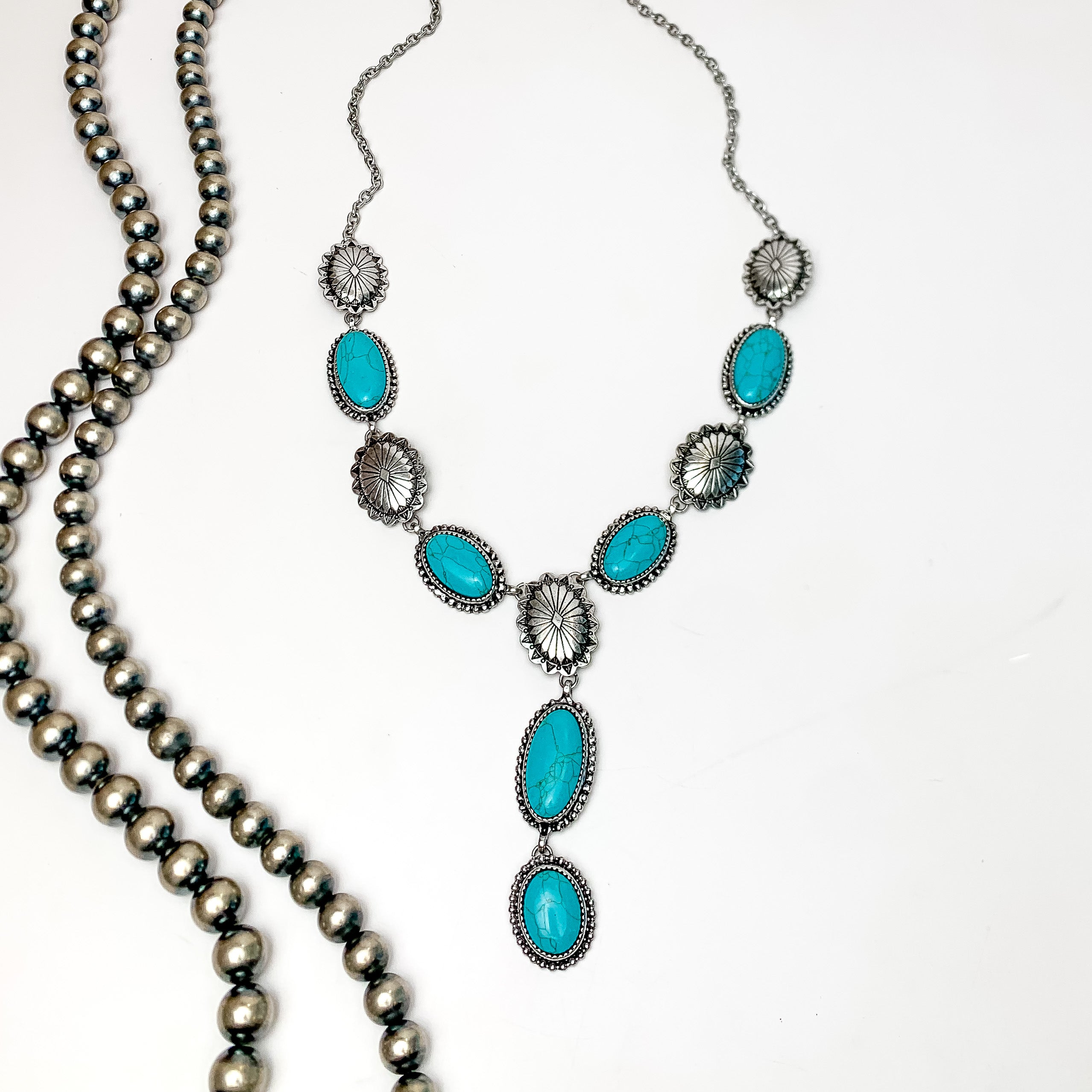 Western Oval Turquoise and Silver Tone Y Necklace. Pictured on a white background with Navajo beads on the left.