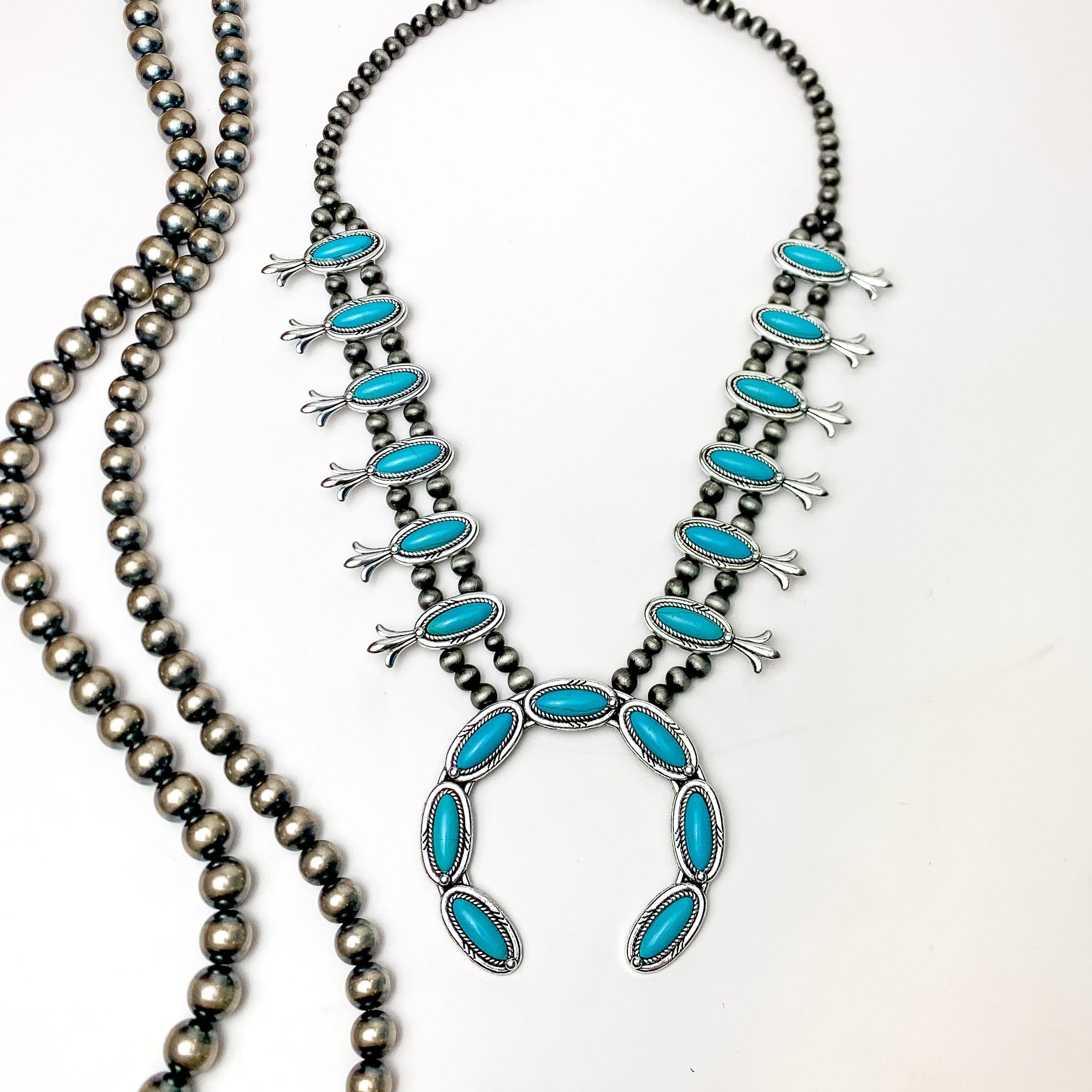 Silver Tone Pearl Squash Blossom Necklace in Turquoise. Pictured on a white background with Navajo beads on the left.