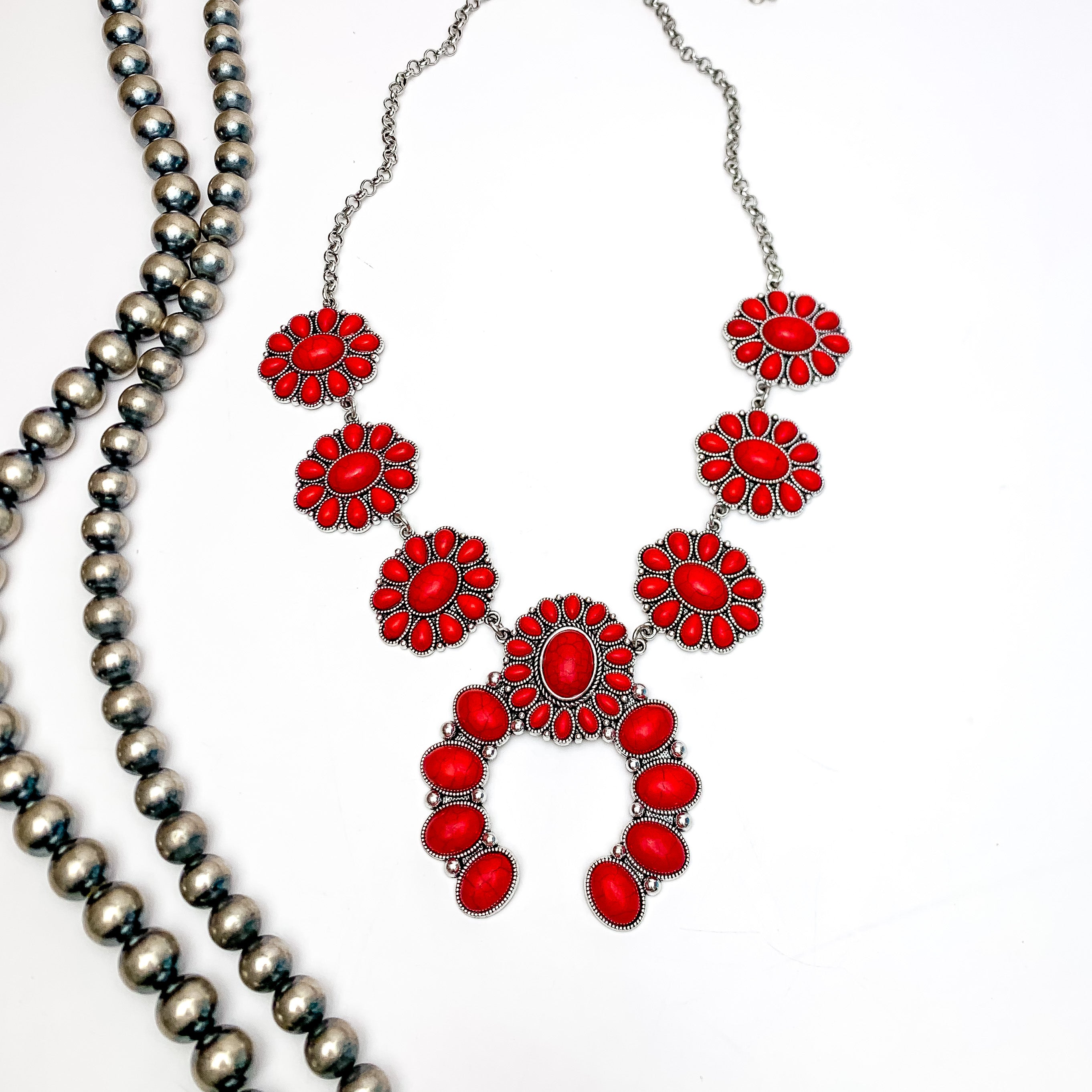 The Western Way Squash Blossom Necklace in Red. Pictured on a white background with Navajo beads on the left.