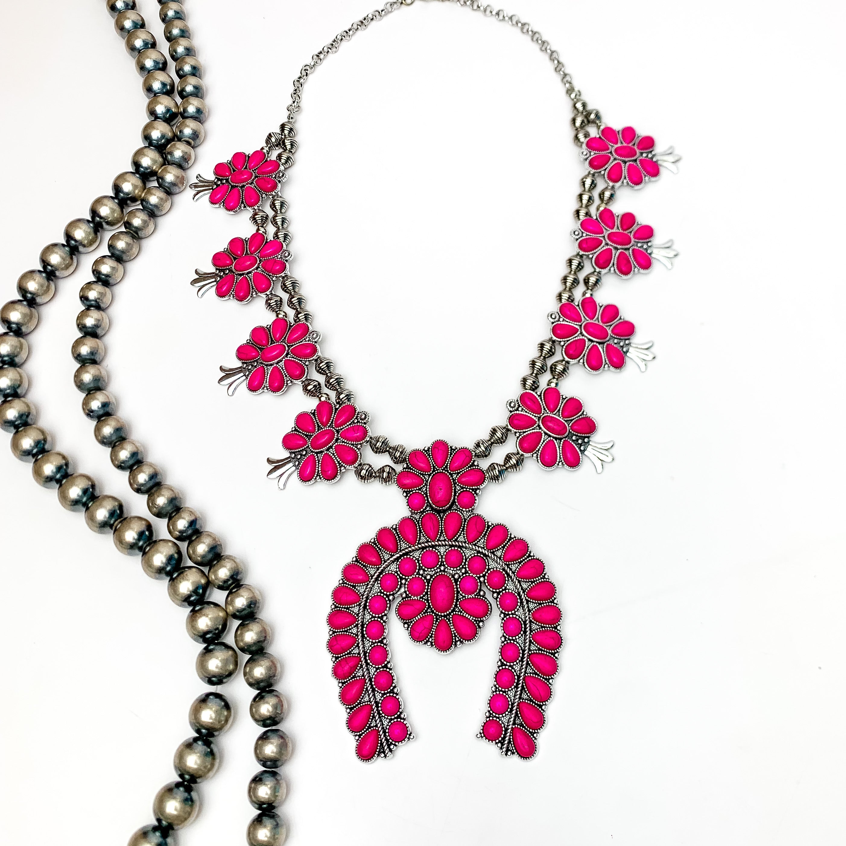 Western Women Squash Blossom Necklace in Hot Pink. Pictured on a white background with Navajo beads on the left.