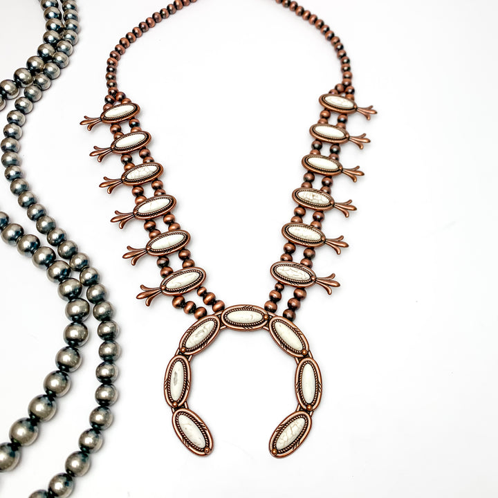 Copper Tone Pearl Squash Blossom Necklace With Stones in Ivory. Pictured on a white background with Navajo beads on the left.