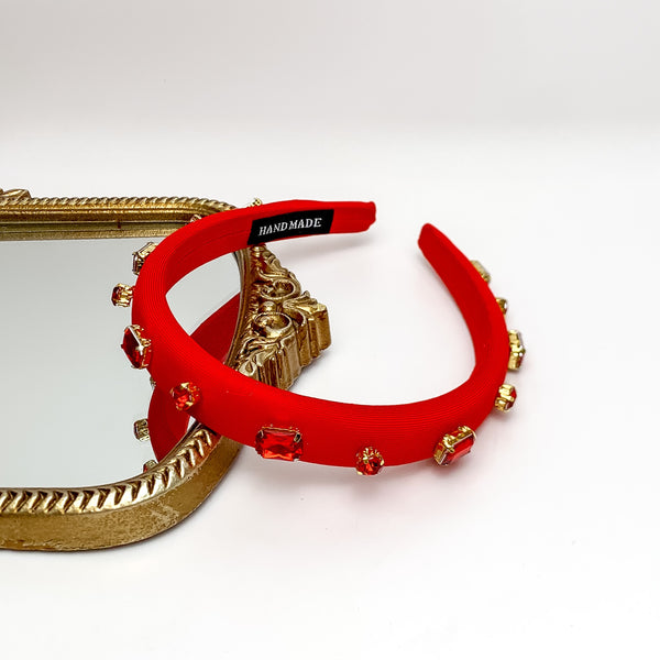 Crystal Detailed Headband in Red. Pictured on a white background with part of the headband on a gold trimmed mirror.