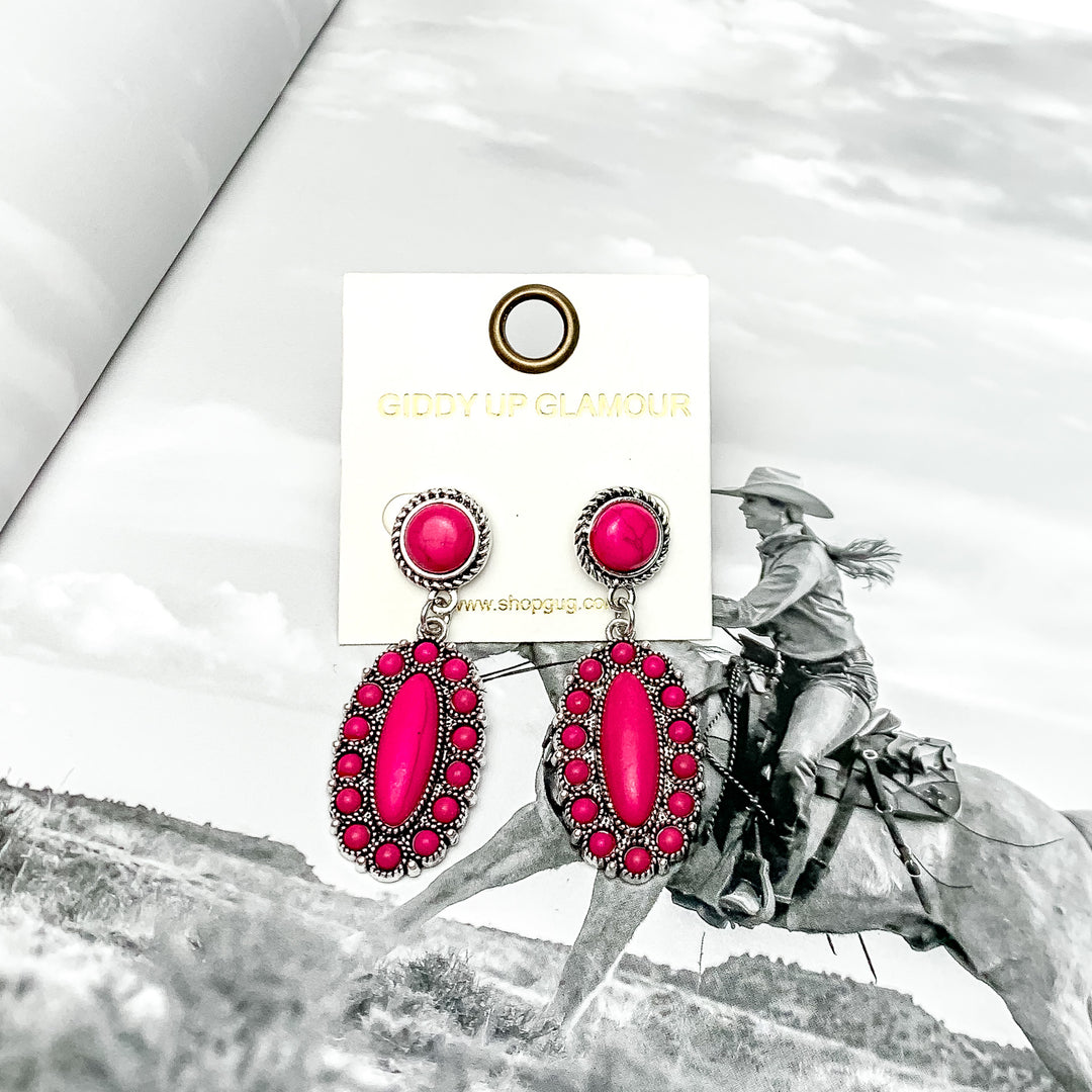 Circle Post Earrings with Oval Cluster and Stones in Hot Pink. Pictured on a book with a western background.