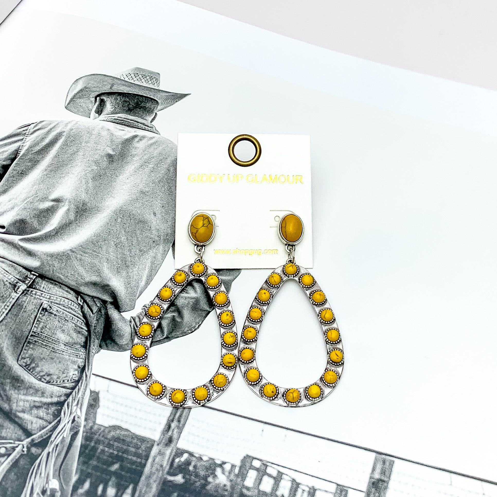 Western Open Teardrop Earrings With Stones in Yellow. Pictured on a western background picture. 