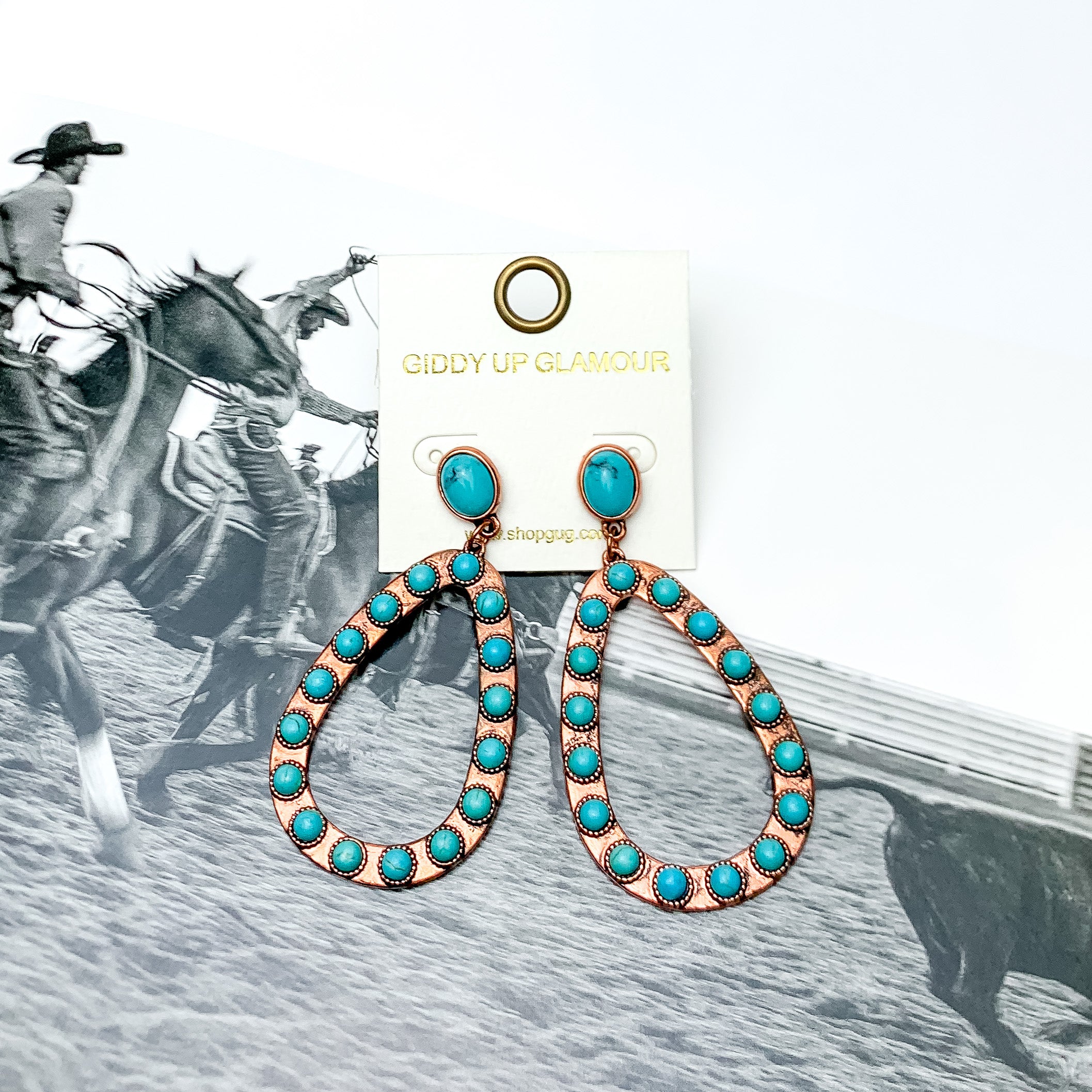 Western Copper Tone Open Teardrop Earrings With Stones in Turquoise. Pictured on a western background picture.