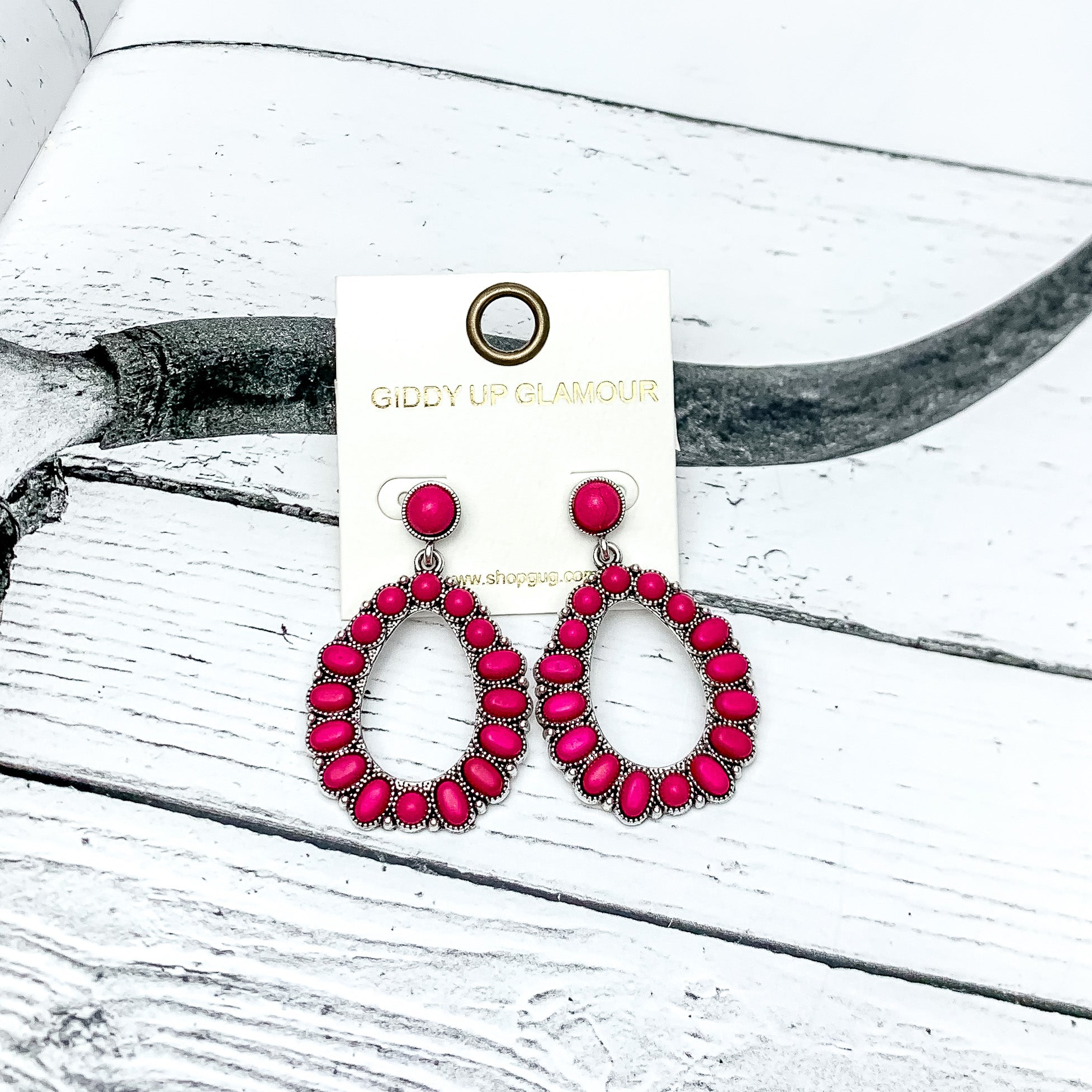 Small Circle Post Open Teardrop Earrings with Stones in Hot pink. These earrings are pictured on a western background.