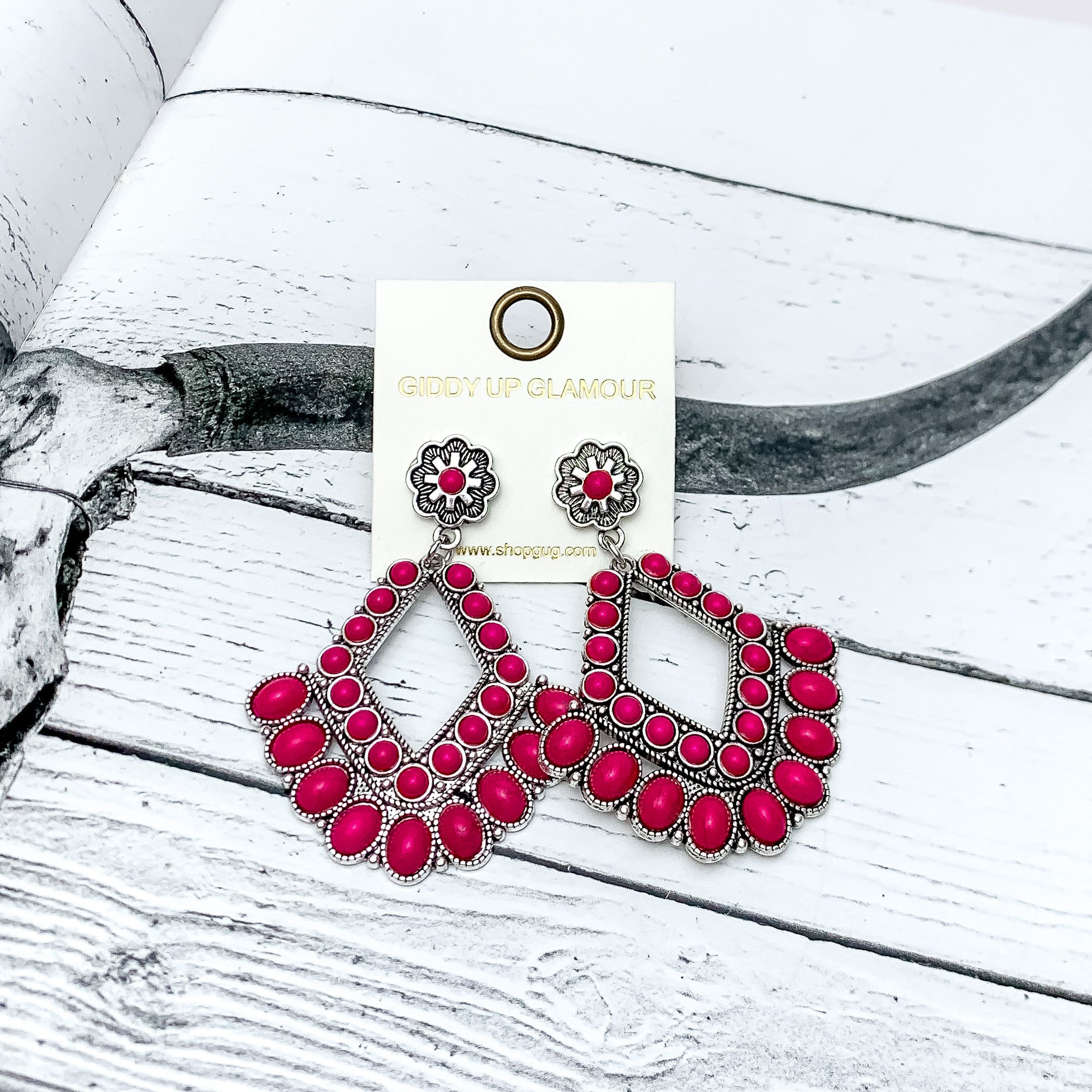 Western Chandelier Earrings in Hot Pink. Pictured on a white background with the earrings on a western background.