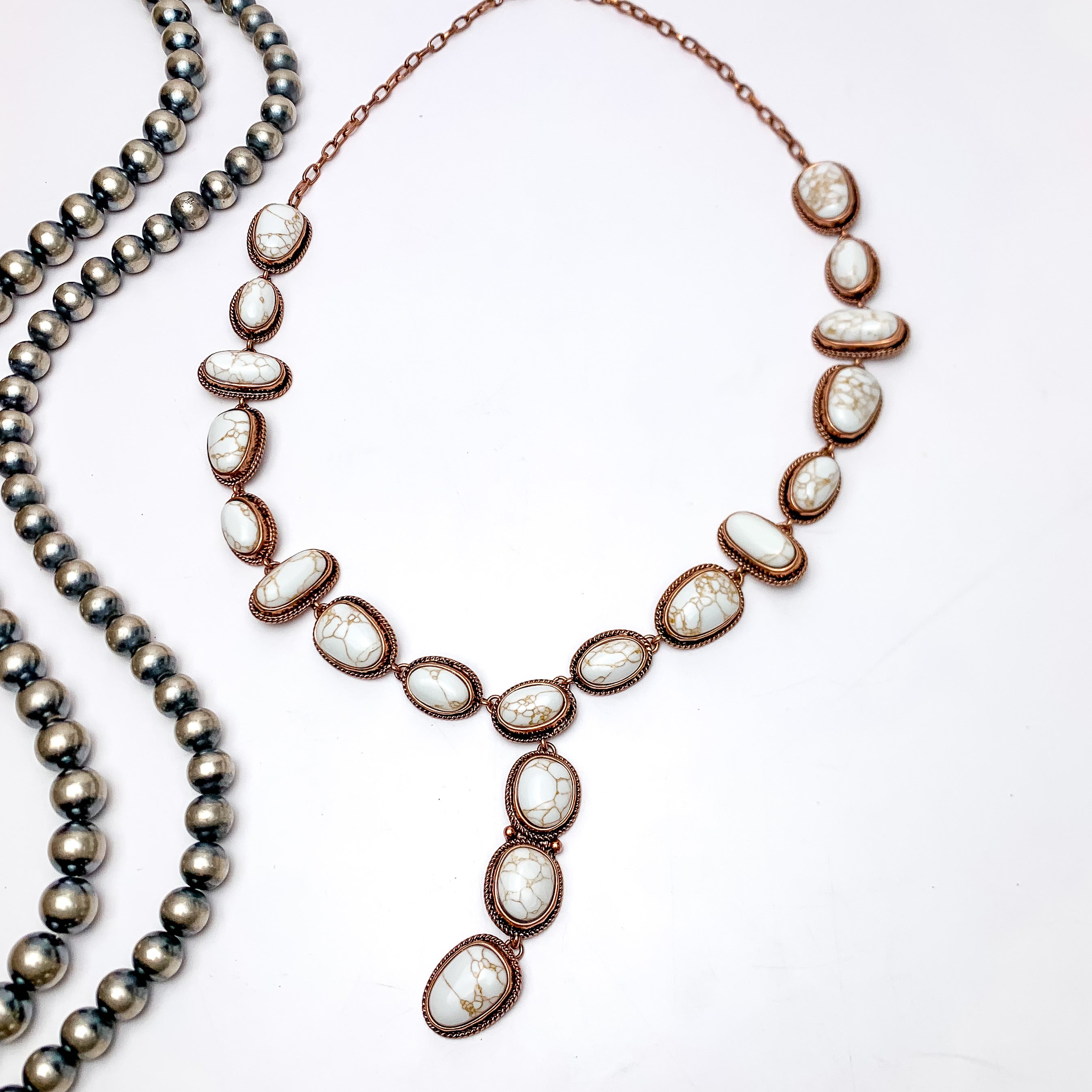 Western Stone Lariat Necklace With Ivory Stones. This copper and ivory necklace is laying on a white background with Navajo pearls to the left of it for decoration.