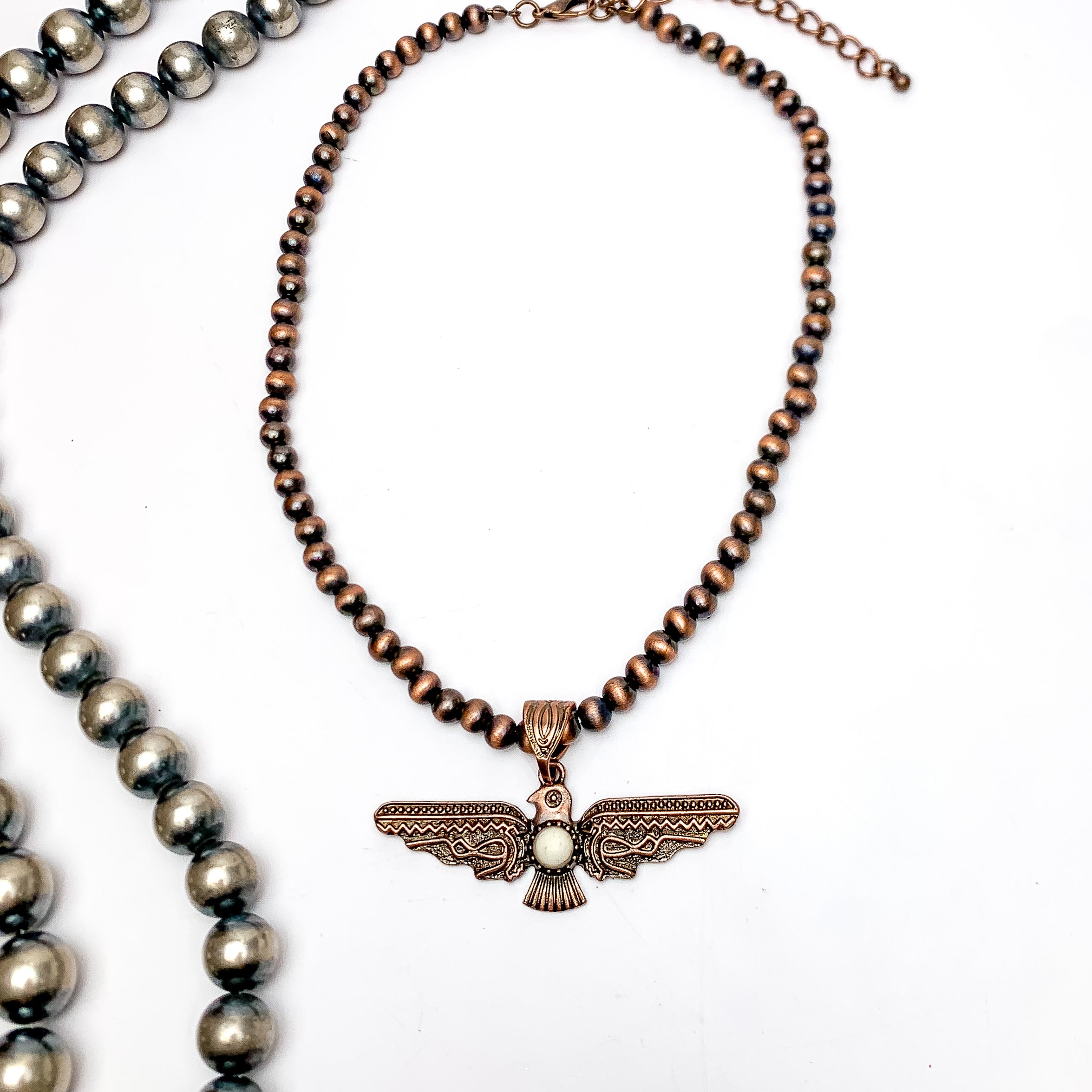 Thunder Bird Pendent Copper Tone Beaded Necklace. This silver beaded necklace with a turquoise stone is pictured on a white background with Navajo beads on the left side.
