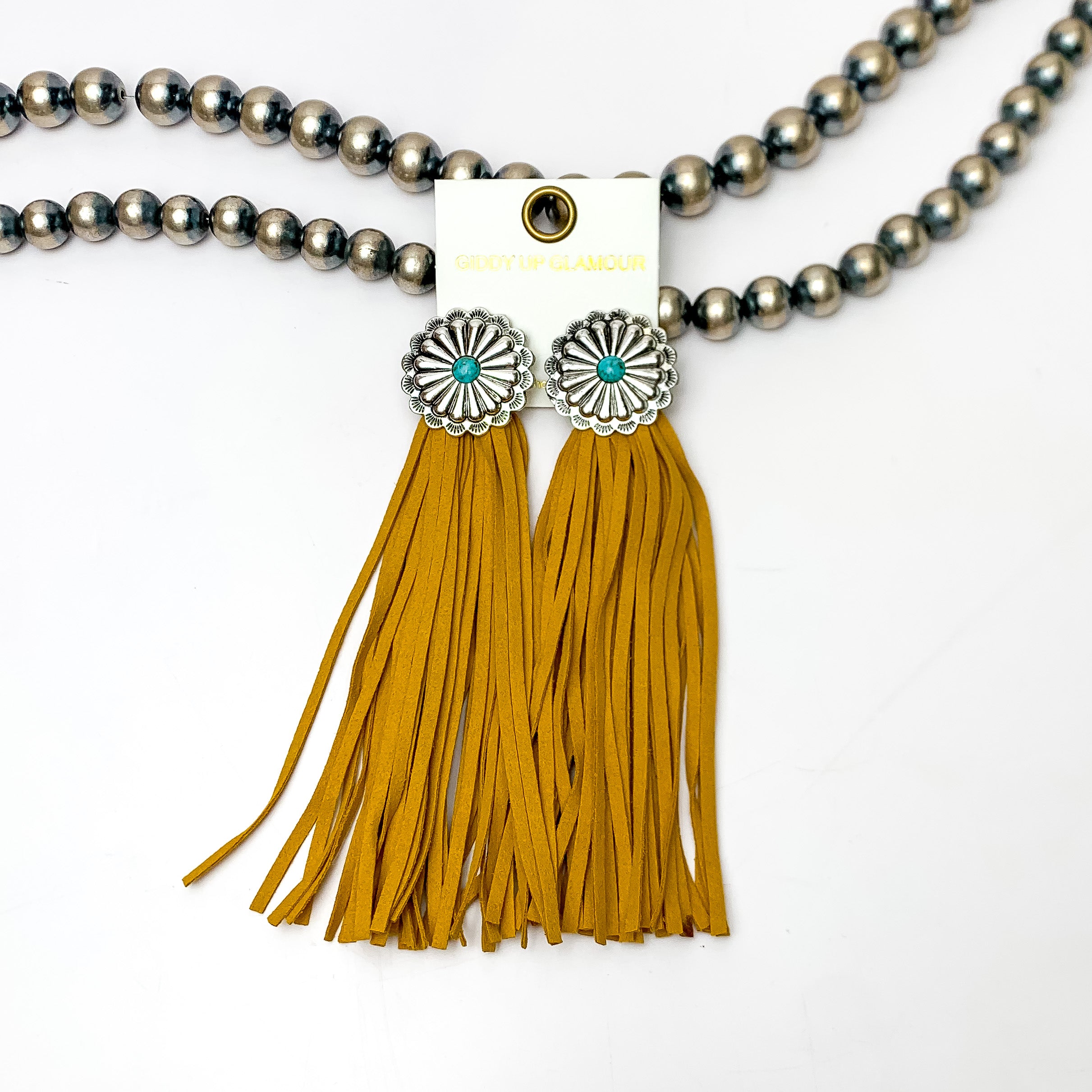 Rodeo Runway Tassel Earrings in Yellow. These tassel earrings are pictured on white background with them laying on Navajo peals.