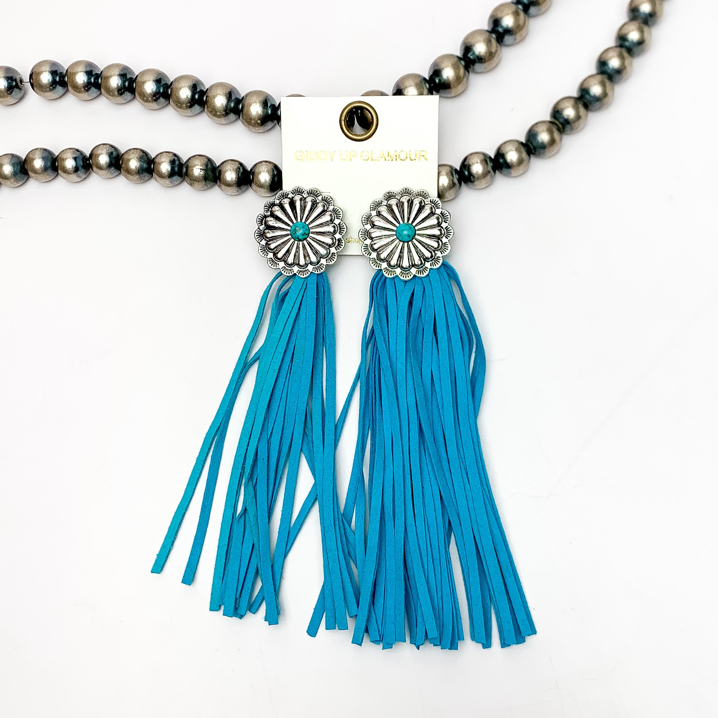 Rodeo Runway Tassel Earrings in Turquoise Blue. These tassel earrings are pictured on white background with them laying on Navajo peals.