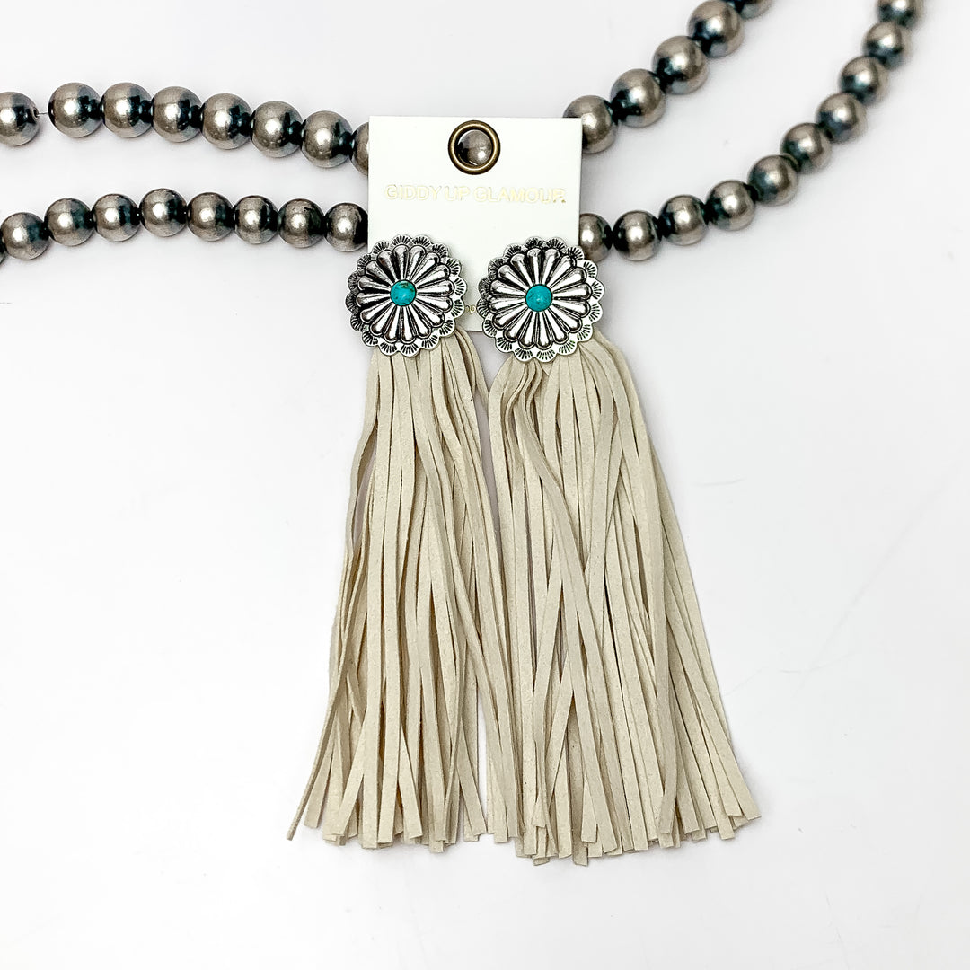 Rodeo Runway Tassel Earrings in Ivory. These tassel earrings are pictured on white background with them laying on Navajo peals.