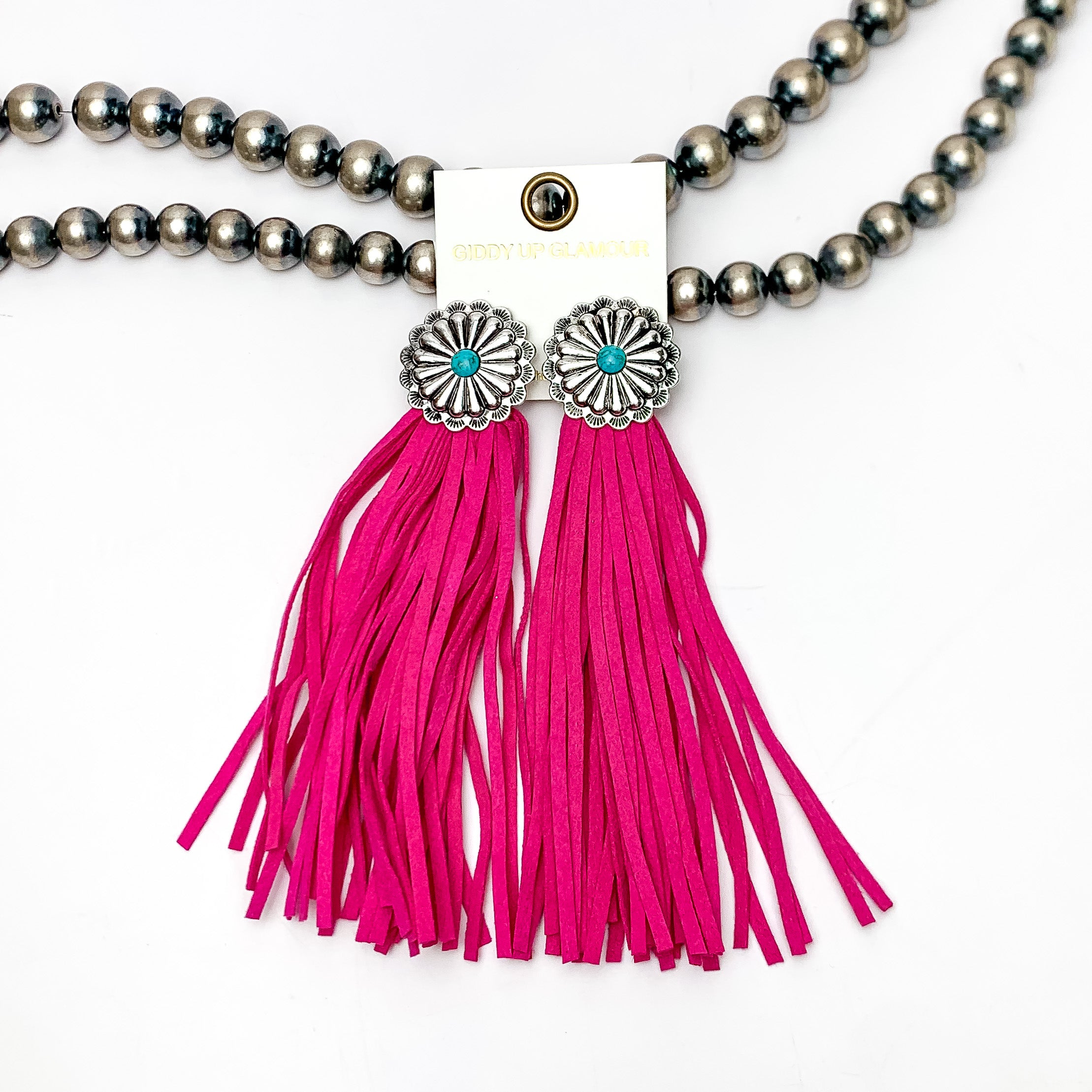 Rodeo Runway Tassel Earrings in Hot Pink. These tassel earrings are pictured on white background with them laying on Navajo peals.