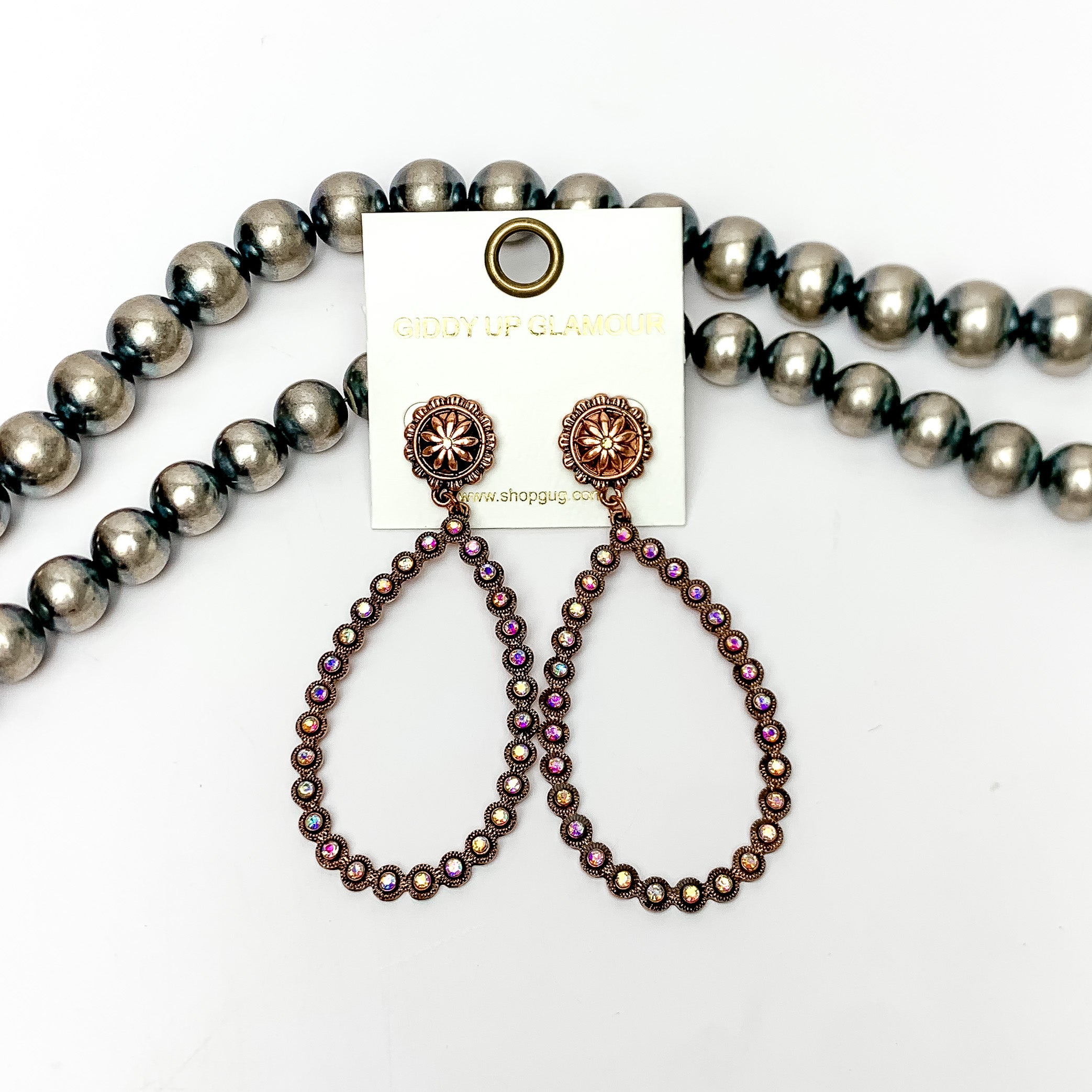 AB Crystal Open Teardrop Earrings in Copper Tone. These open ab crystal teardrop earrings are pictured on a white background with Navajo pearls behind the earrings.