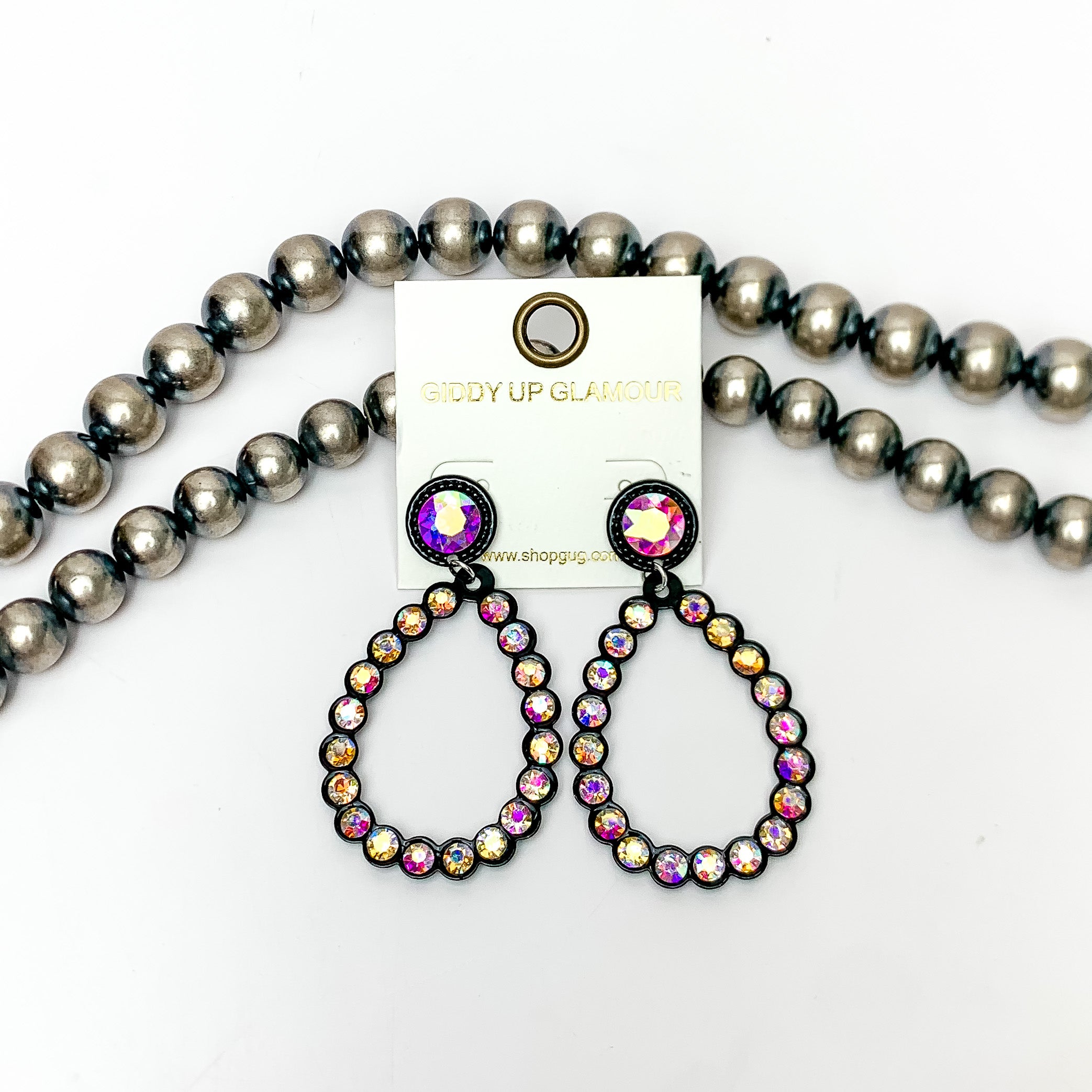 Glitzy Girl AB Crystal Teardrop Earrings in Black. Pictured on a white background with Navajo pearls behind the earrings.