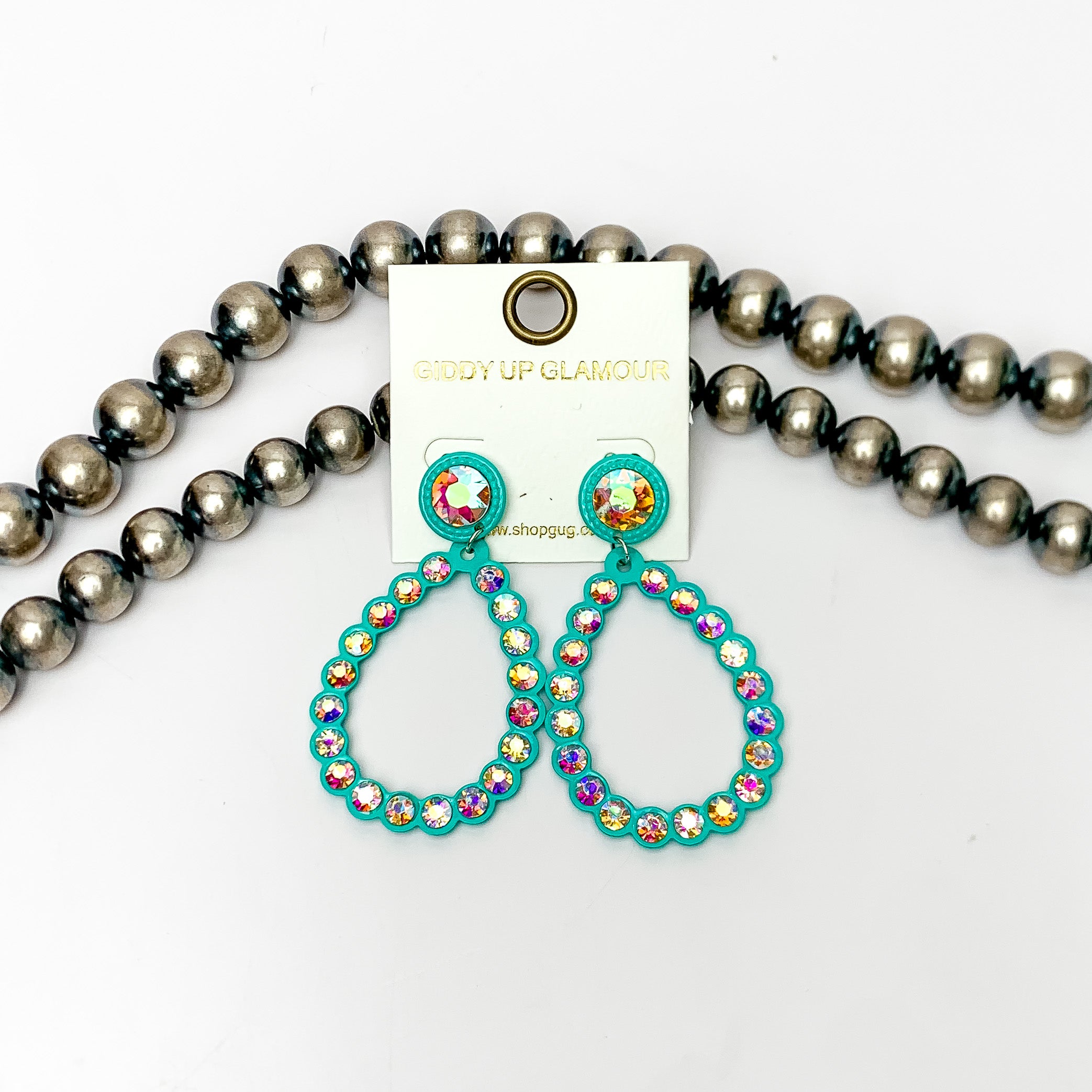 Glitzy Girl AB Crystal Teardrop Earrings in Turquoise. Pictured on a white background with Navajo pearls behind the earrings.