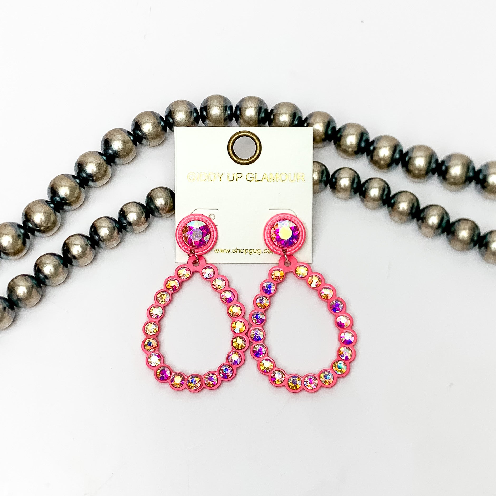 Glitzy Girl AB Crystal Teardrop Earrings in Hot Pink. Pictured on a white background with Navajo pearls behind the earrings.