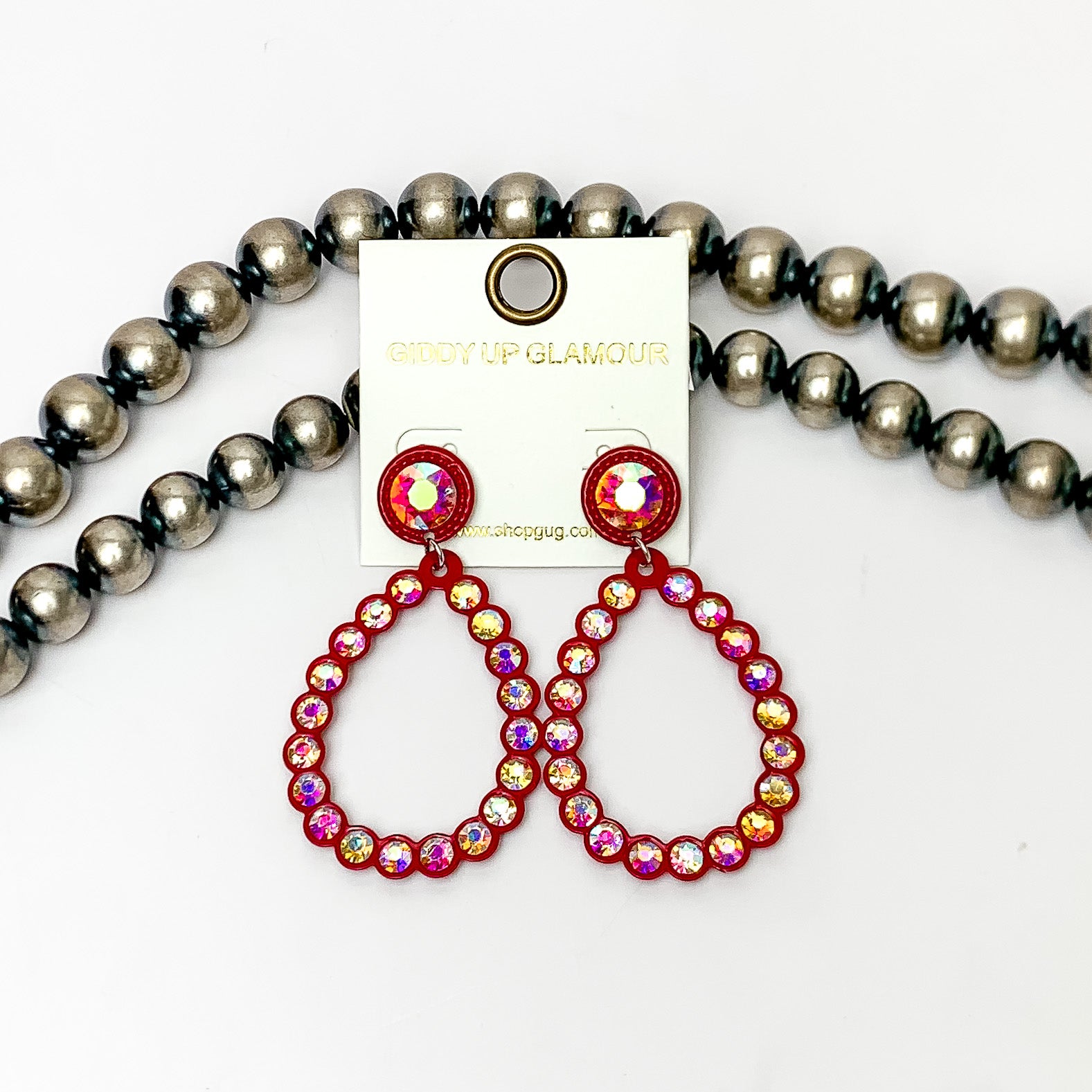 Glitzy Girl AB Crystal Teardrop Earrings in Red. Pictured on a white background with Navajo pearls behind the earrings.