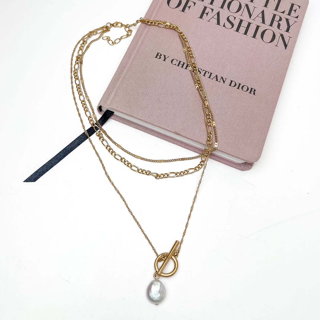 Pretty as a Pearl Gold Tone Chain Necklace. Pictured on a white background with part of the necklace laying on a pink book.