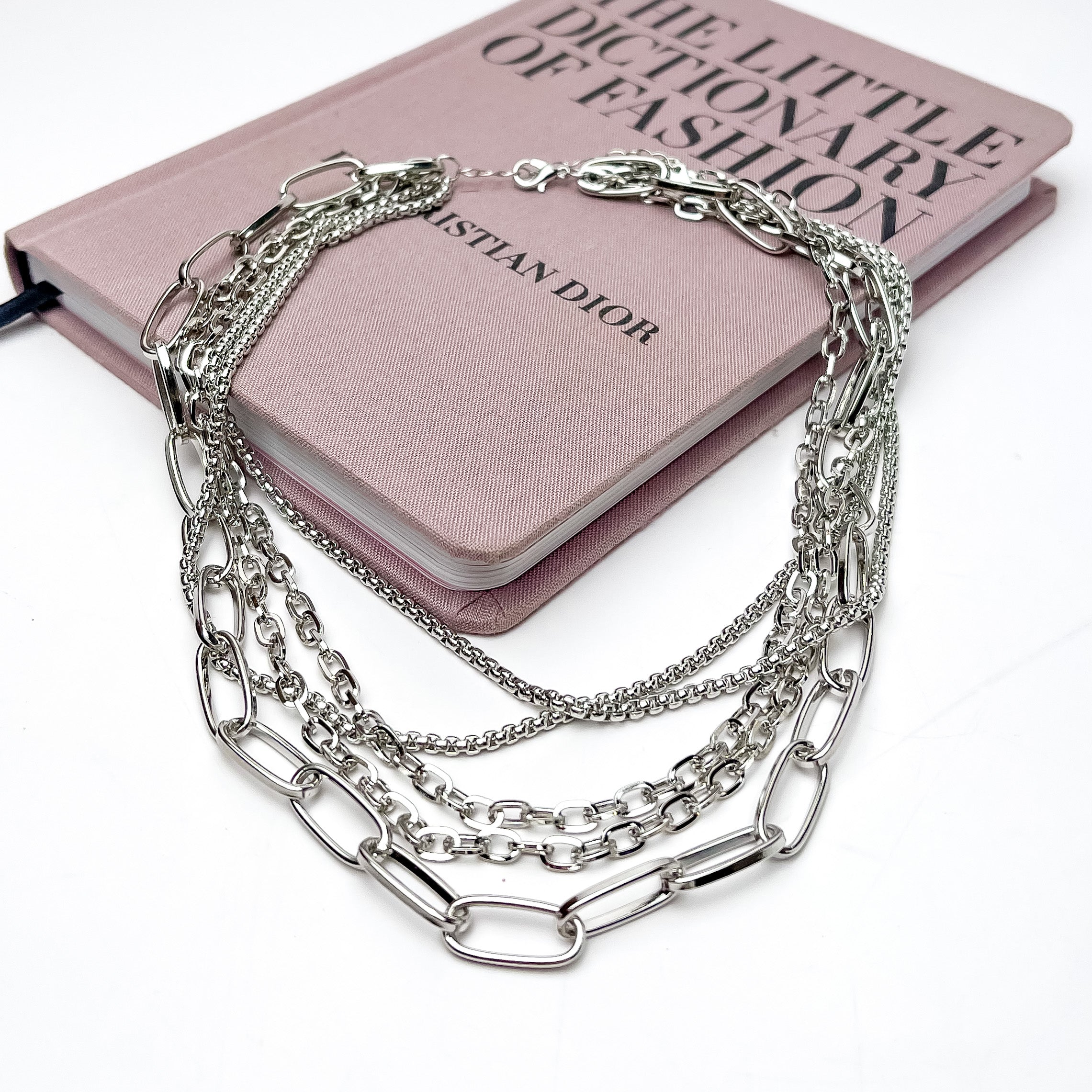 Sophisticated Silver Tone Chain Necklace. This necklace is on a white background with part of it on a pink book.