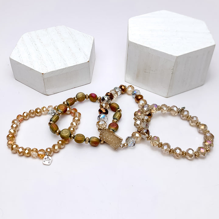 Set of Four | Crystal Beaded Bracelet Set in Gold Tones. These bracecelts are pictured on a white background with two white podiums behind them.
