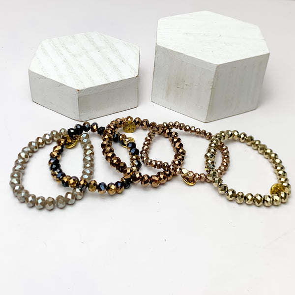 Set of Five | All Nighter Crystal Beaded Bracelet Set in Gold Tones. These bracelets are pictured on a white background with two white podiums behind them.